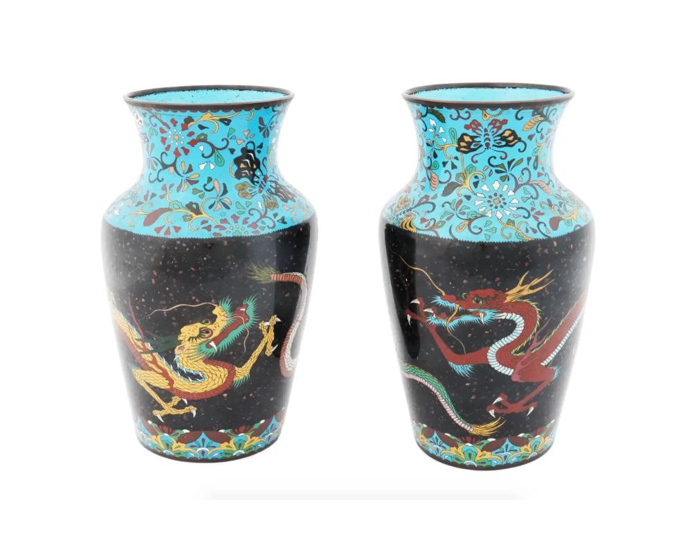 A pair of antique Japanese Meiji Era enamel vases. Circa: Late 19th Century The baluster form vases are enameled with polychrome images of dragons made in the Cloisonne technique on a black ground with gold flecks. The turquoise borders are