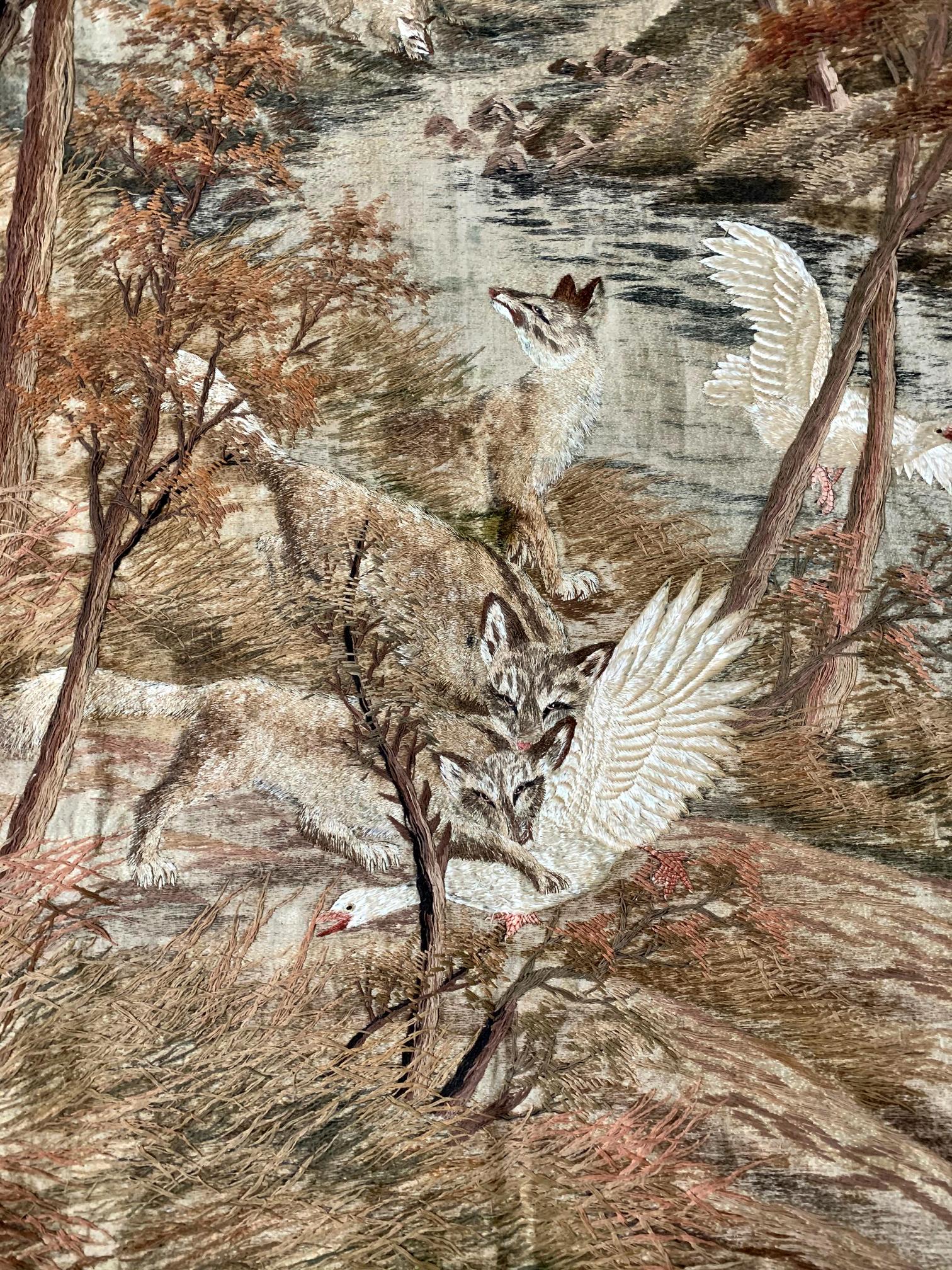 Grande tapisserie japonaise finement brodée avec bordure de brocart, vers les années 1900, période Meiji. La tapisserie représente, dans un style plutôt réaliste, un paysage forestier en automne, flanqué d'une rivière sinueuse. Dans le paysage, des