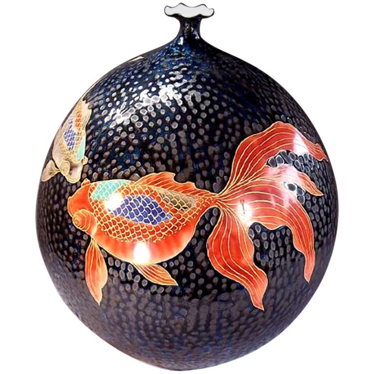 Contemporary large Japanese Imari hand-painted black porcelain vase with elegant gold fish in vivid red, turquoise and cream, with intricate gold details, swimming against a dimpled black background, a signed piece from the signature fish collection
