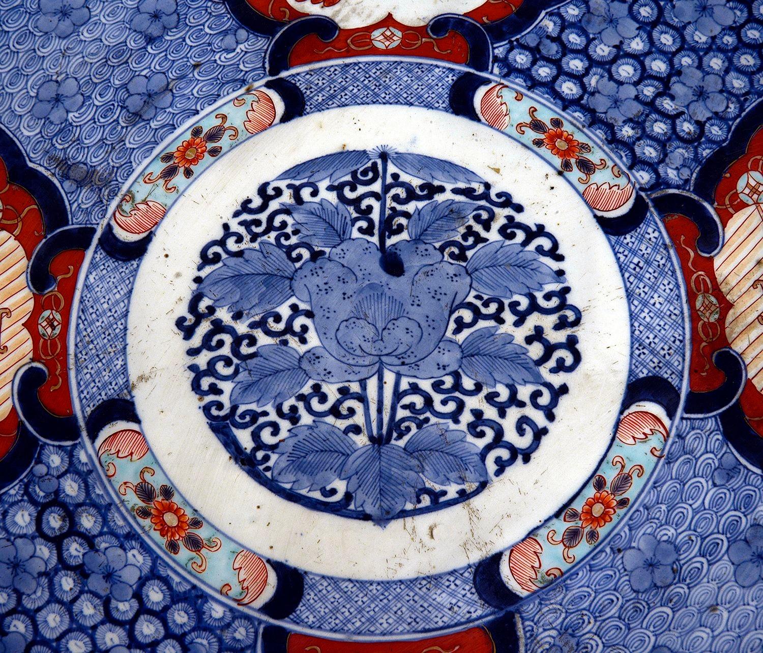 Grand chargeur japonais en porcelaine Imari, représentant des motifs classiques, avec un fond bleu et quatre panneaux rouges avec des savants, des enfants et des créatures mythiques.

Lot 82 N/H