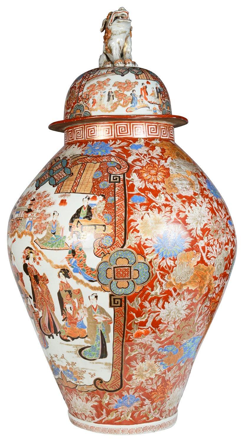 A large and impressive 19th Century Japanese Imari lidded vase. Having a wonderful mythical Foo Dog finial to the lid, classical orange ground with scrolling foliate and floral decoration, inset hand painted panels depicting Geisha girls and