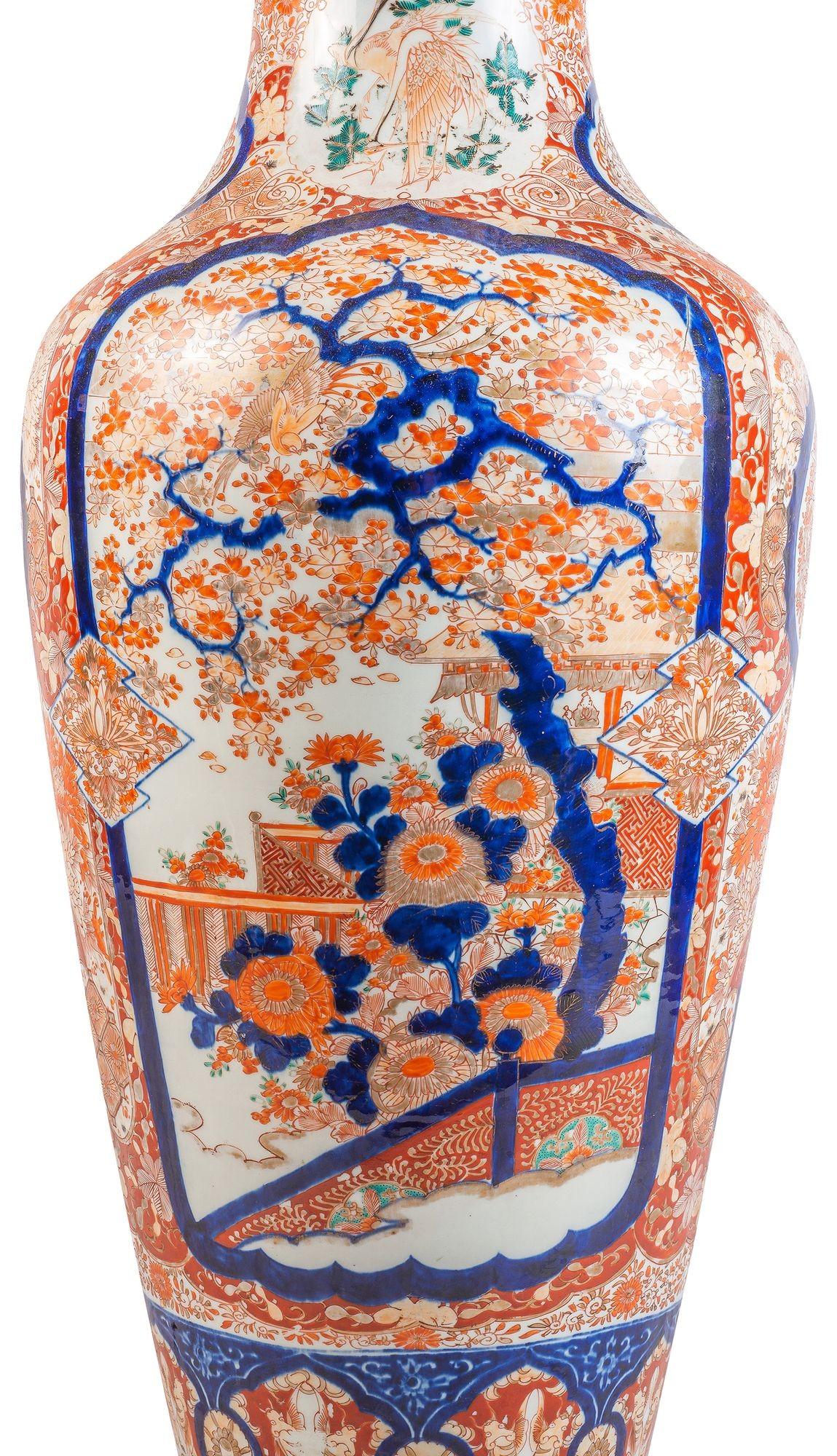 Un grand et impressionnant vase japonais Imari du 19e siècle, aux magnifiques couleurs traditionnelles orange et bleu, avec un motif classique, des bordures et un fond feuillus. Panneaux encastrés peints à la main d'arbres en fleurs exotiques, de