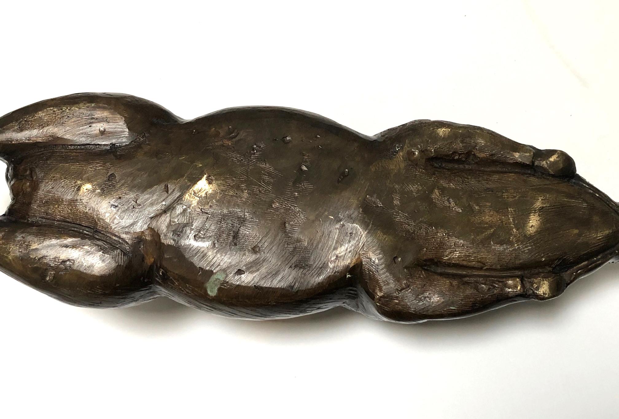 Crafted of cast bronze with nice patina depicting a well-detailed reclining pig with extended legs, arching ears, curled tail, and fur details throughout.