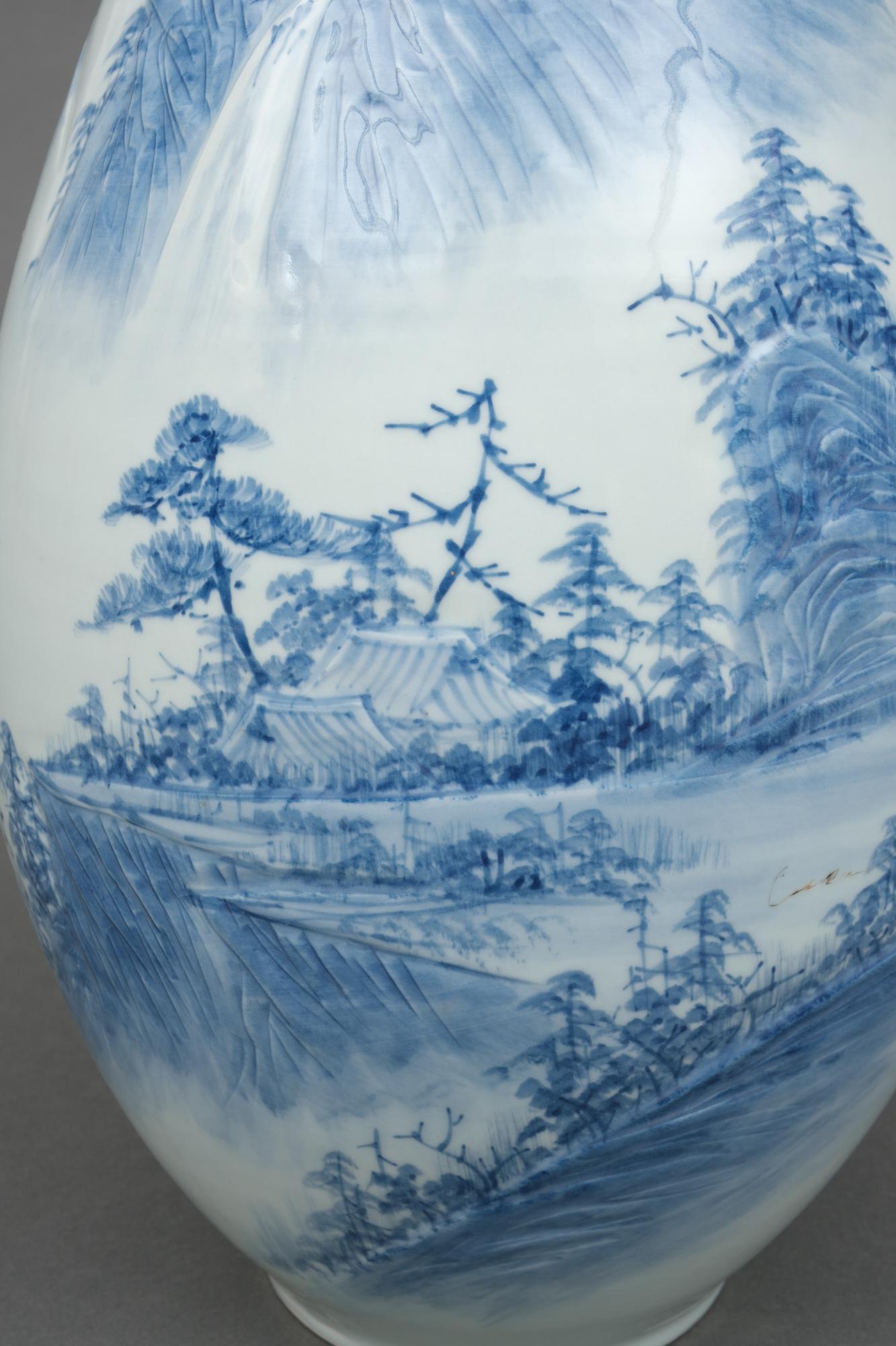 Très grand vase en porcelaine de forme ovoïde avec un beau motif de paysage montagneux bleu et blanc accentué par des détails en bas-relief. Le haut du vase se termine par un élégant petit col.

Votre regard se pose d'abord sur une maison