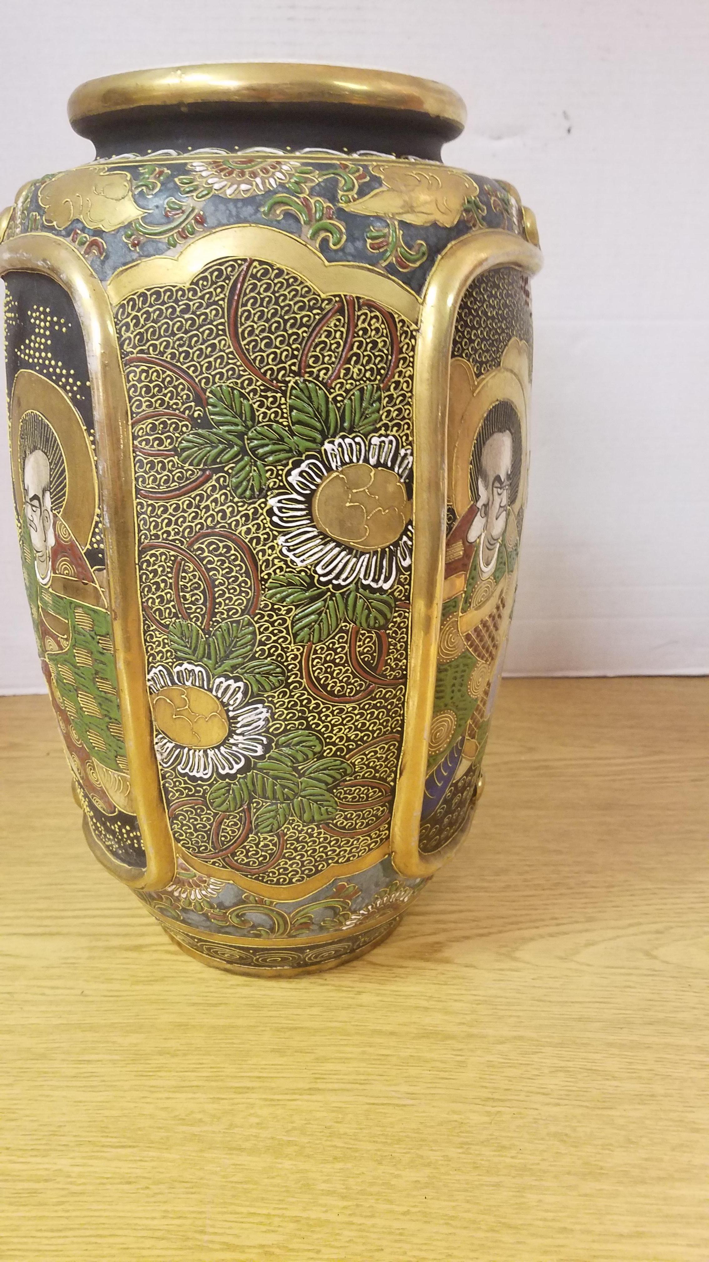 Beautifully detailed and hand painted Japanese Satsuma vase. The dark matte background accentuates the with vibrant gold gilding and rich colors in the painting. Some of the gilding is raised for a 3 dimensional look as well as the raised detail of