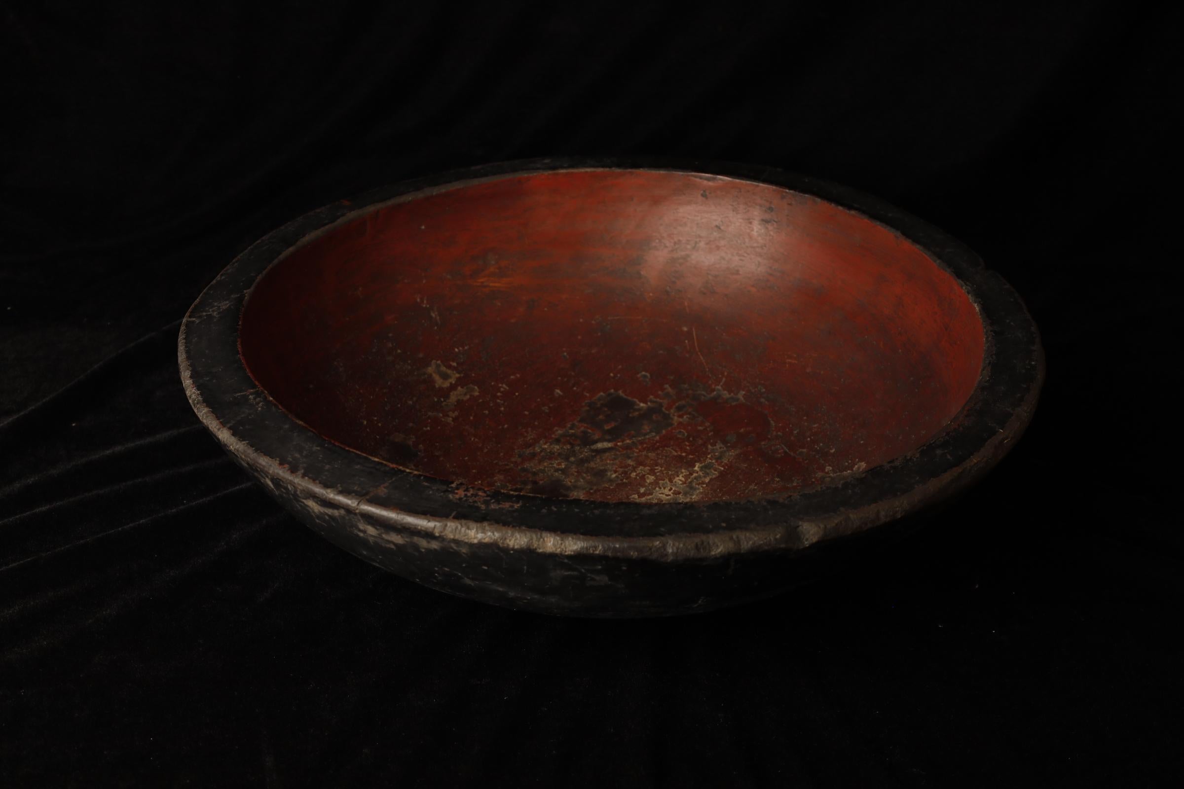 This large antique Japanese wooden kneading bowl is a unique piece with a rich history. Measuring 51 cm in diameter, the bowl has been in use for many years, as evidenced by its worn yet beautiful patina. The interior is coated with a deep red