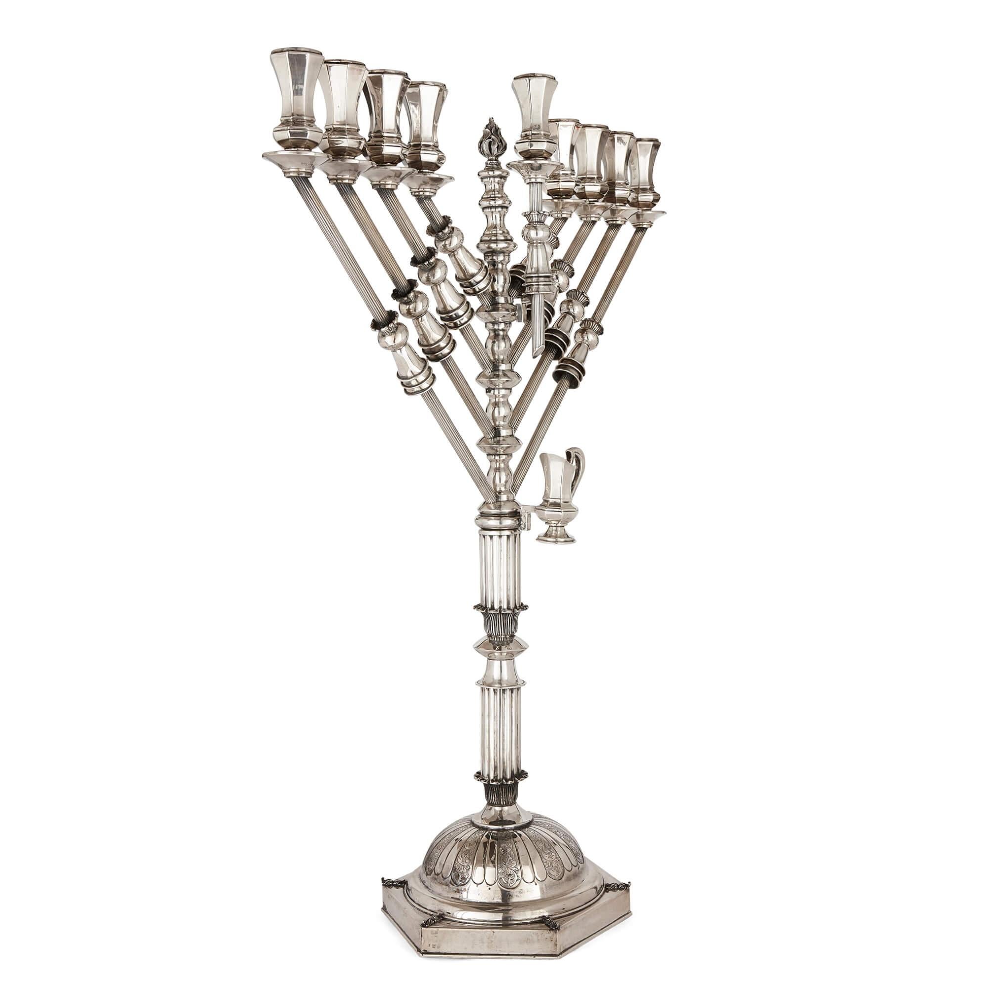 Large Judaica Hanukkah Menorah in sterling silver 
Israeli, 20th Century
Height 104cm, width 78cm, depth 33cm
Weight 8kg 204g

Of a notably large size, this Hanukkah menorah combines geometric and foliate decoration.

The central stem is separated
