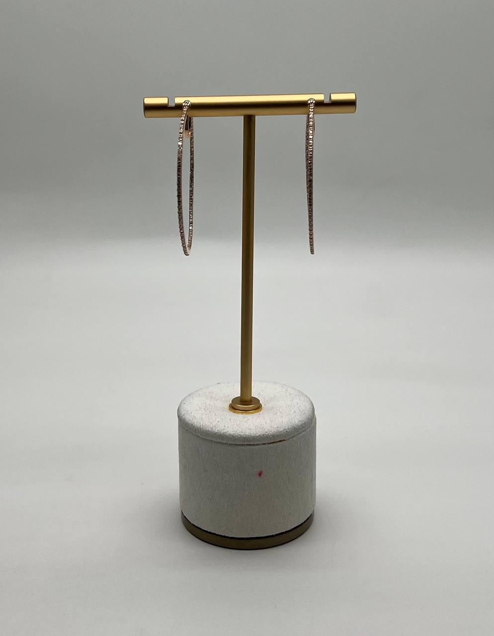 These sophisticated earrings, each earring feature a slender, elongated hoop design encrusted with shimmering diamonds.
The hoops are suspended from a sleek, minimalist gold bar, adding a modern touch.
The stones are meticulously set, creating a