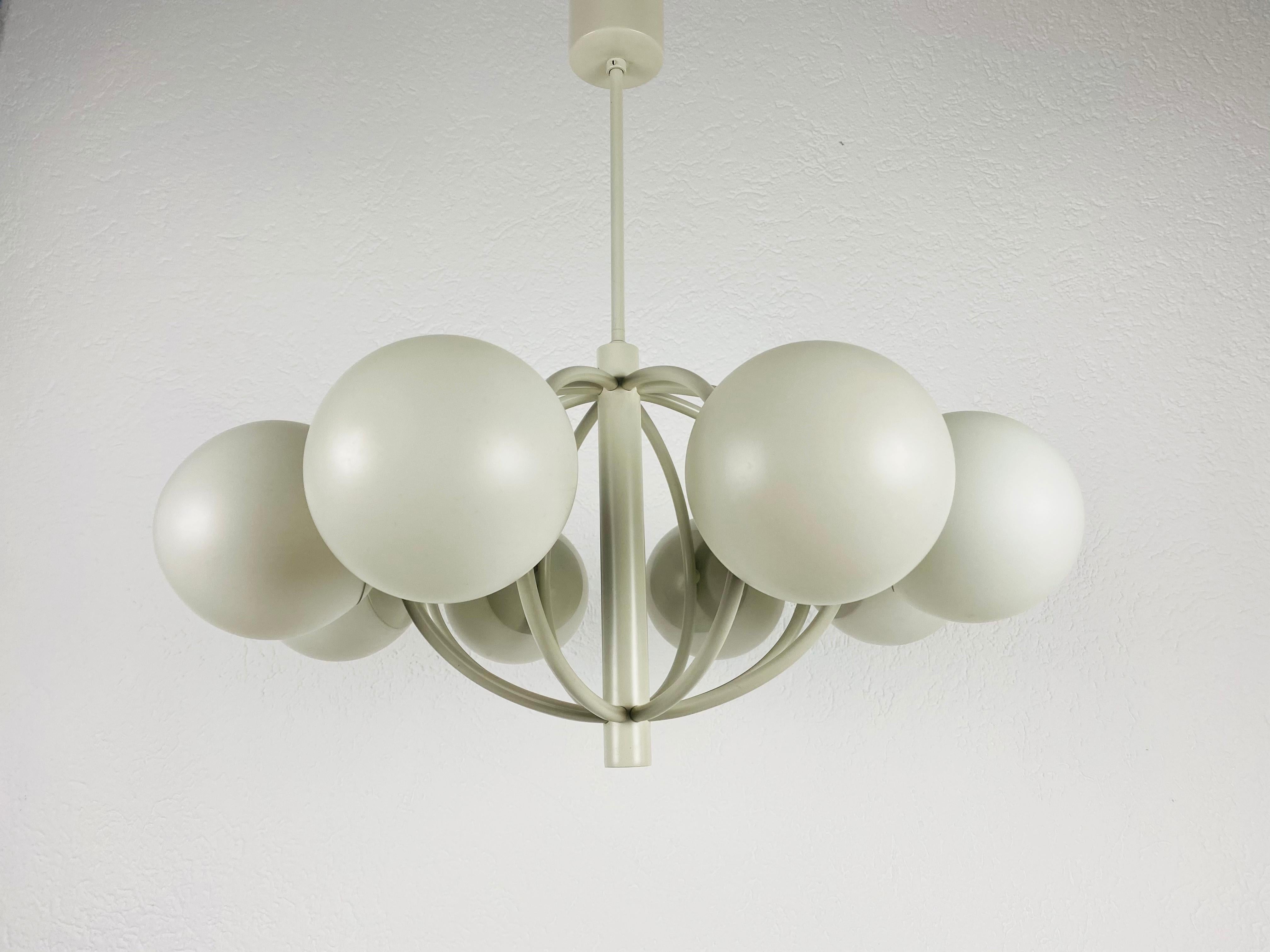 A midcentury chandelier by Kaiser made in Germany in the 1960s. It is fascinating with its Space Age design and eight opaque balls. The white circular body of the light is made of full metal, including the arms. White bar with white canopy.


The