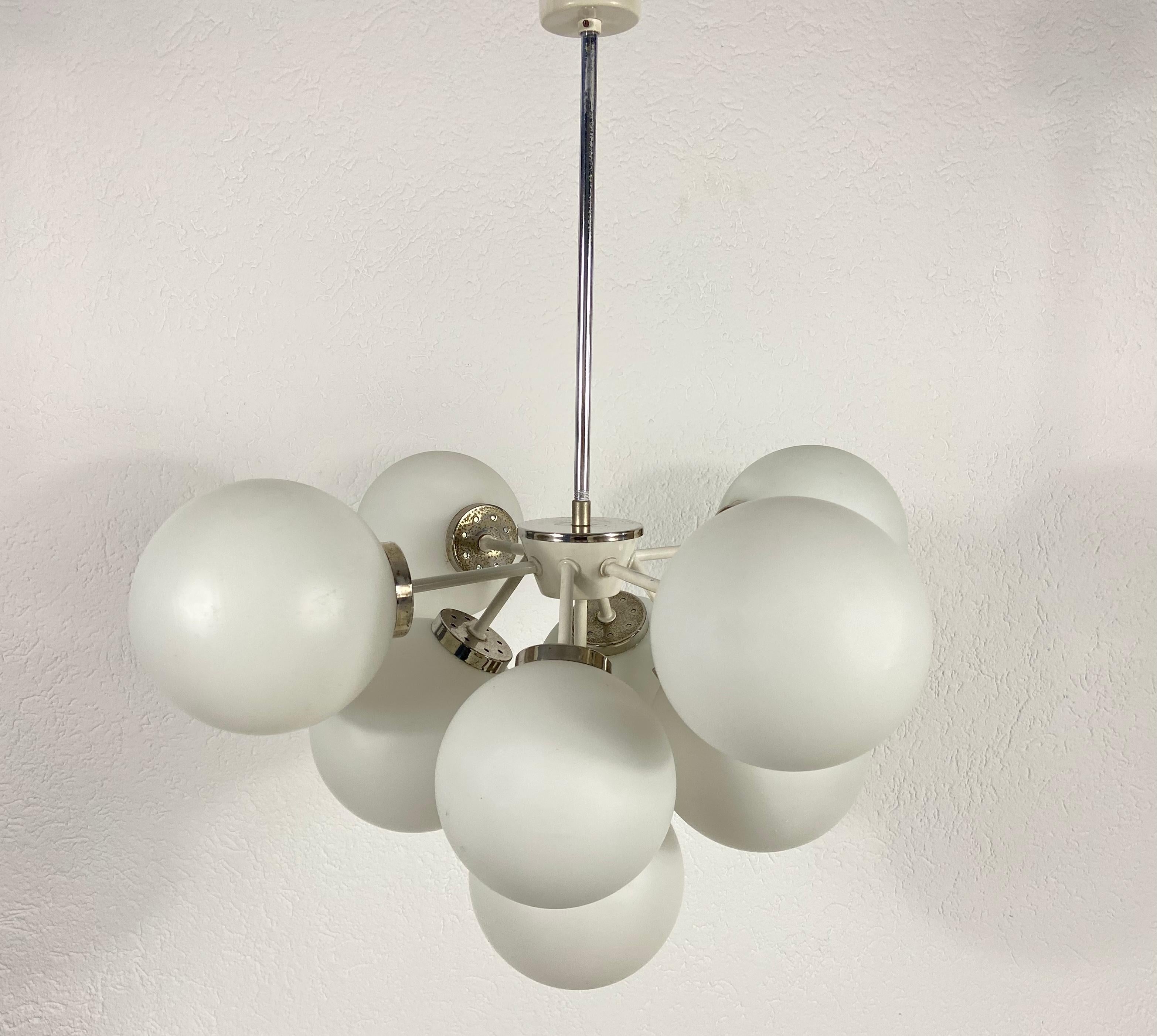 A midcentury chandelier by Kaiser made in Germany in the 1960s. It is fascinating with its Space Age design and nine opaque balls. The white circular body of the light is made of full metal, including the arms. White bar with white canopy.


The