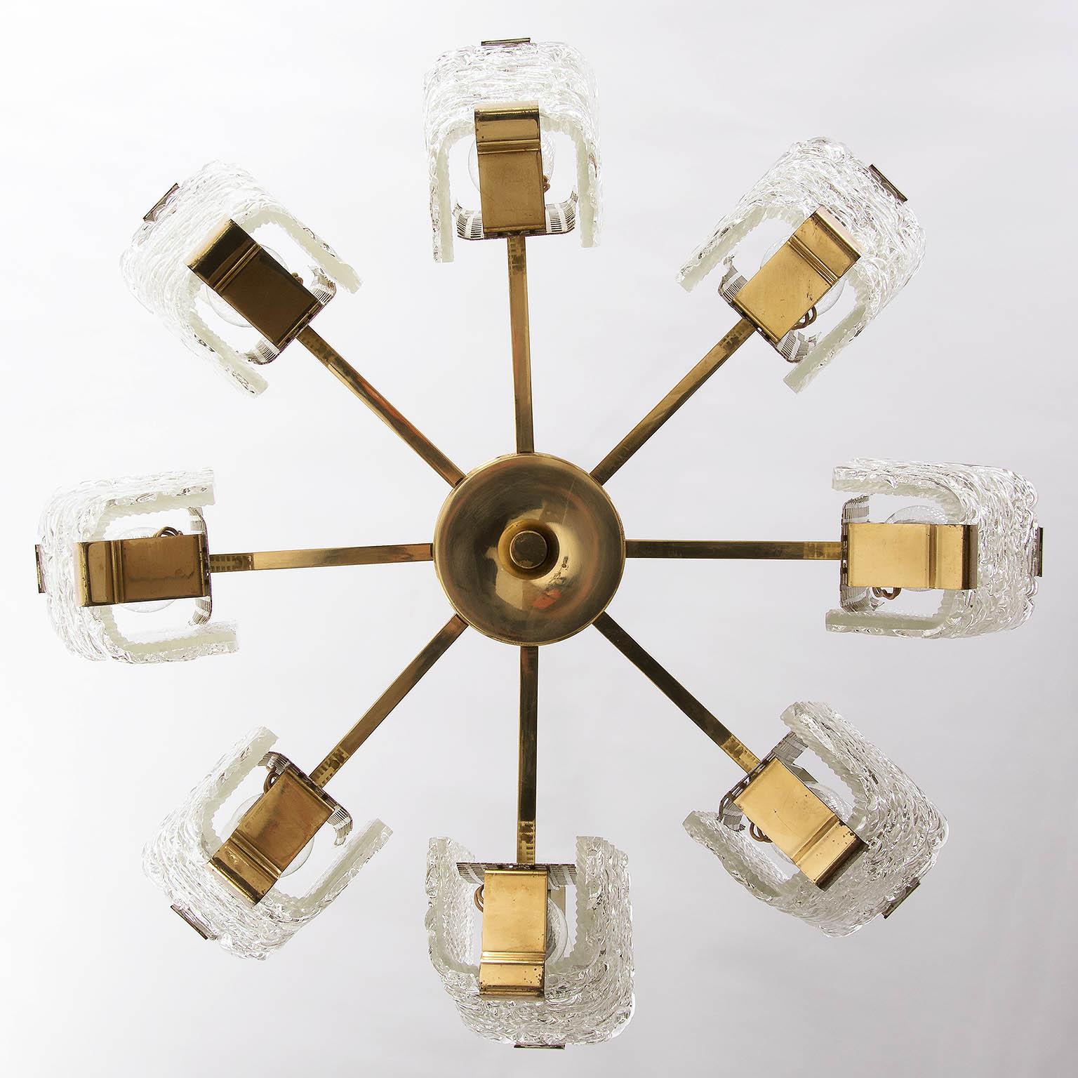 An impressive handmade and large chandeliers by J.T. Kalmar, Austria, manufactured in midcentury, circa 1960 (late 1950s or early 1960s).
The fixture is made of polished brass in a warm tone, textured cast glass and perforated white paint metal. 
It