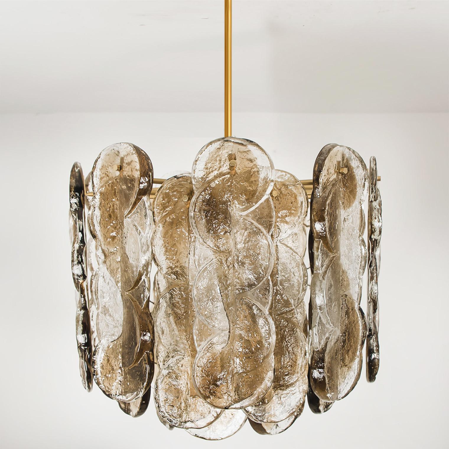 Hochwertiger Murano-Glaskronleuchter von Kalmar, 1960er Jahre, geräuchertes Wirbeleisglas, klare, gedrehte Kristallglasscheiben mit einem hellen, goldenen, bernsteinfarbenen Streifen darin.

Kalmar war der bedeutendste Produzent von hochwertigen