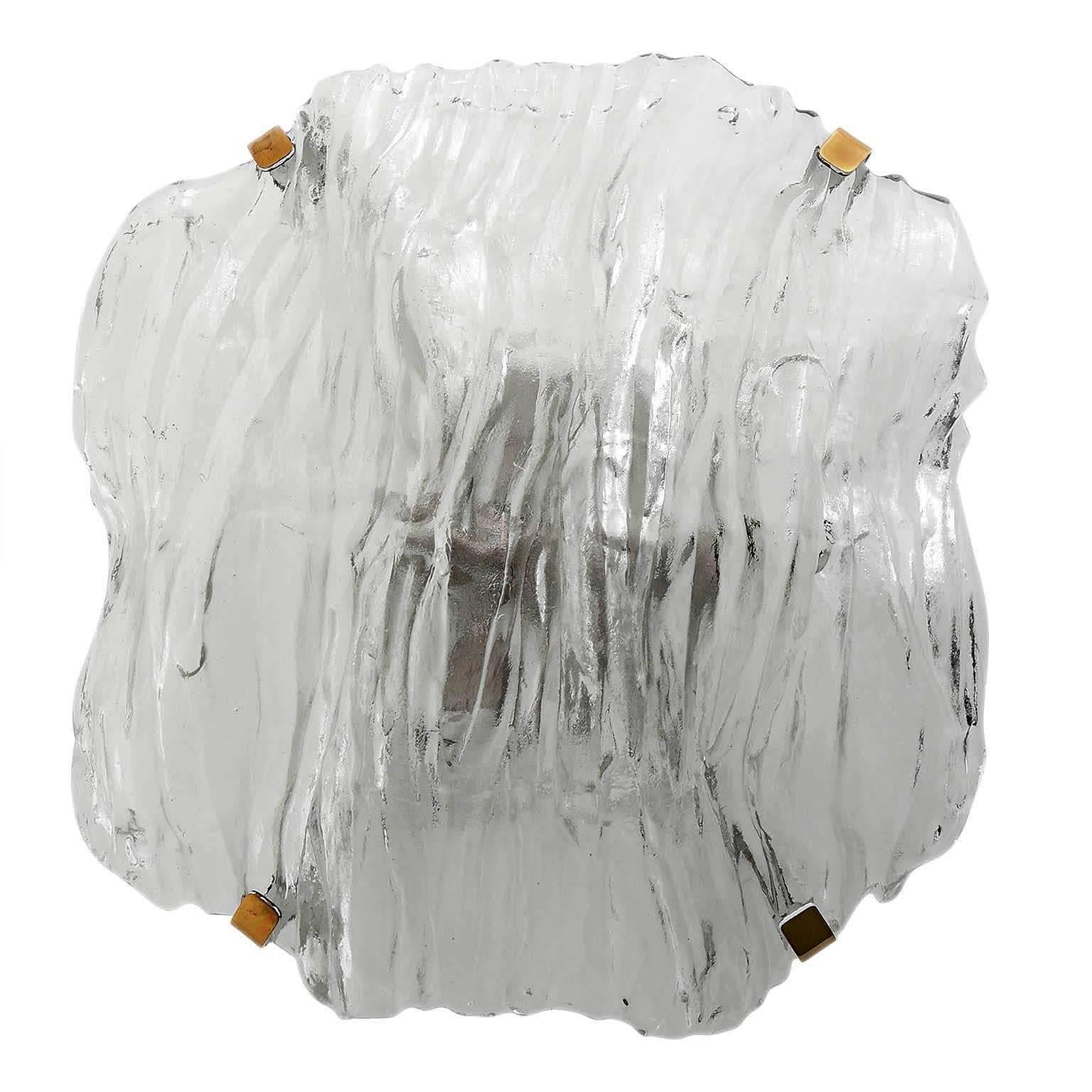 A large and rare flush mount light by Kalmar, Austria, manufactured in Mid-Century, circa 1970 (late 1960s or early 1970s).
An organic shaped clear Murano glass piece is held with four polished brass brackets on a white painted metal backplate.
The