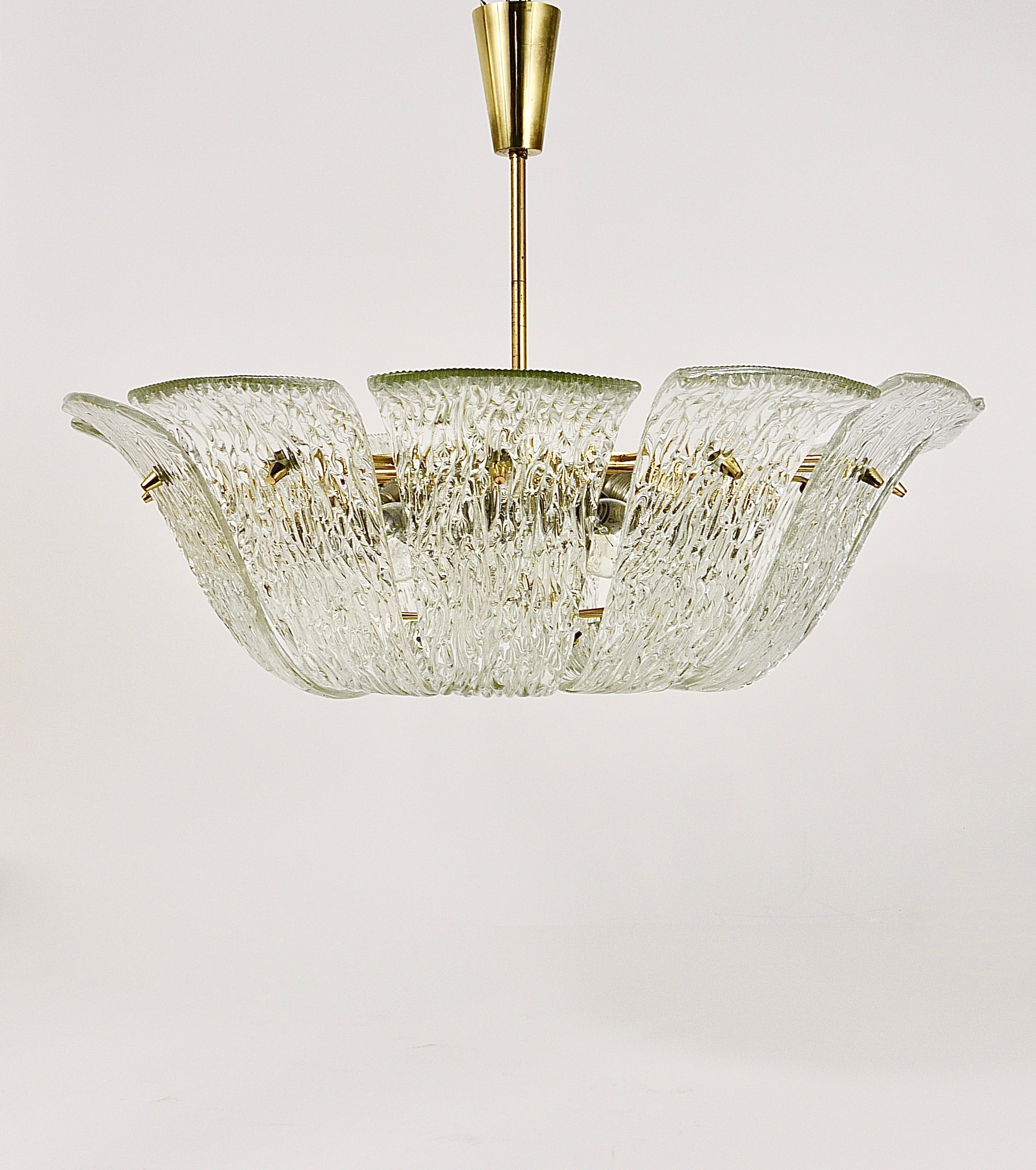 A very beautiful and large 29 inches diameter Austrian modernist brass chandelier from the 1950s, manufactured by J.T. Kalmar Vienna. This charming and elegant vintage chandelier has 12 pieces of lovely curved textured clear glasses, which remind of