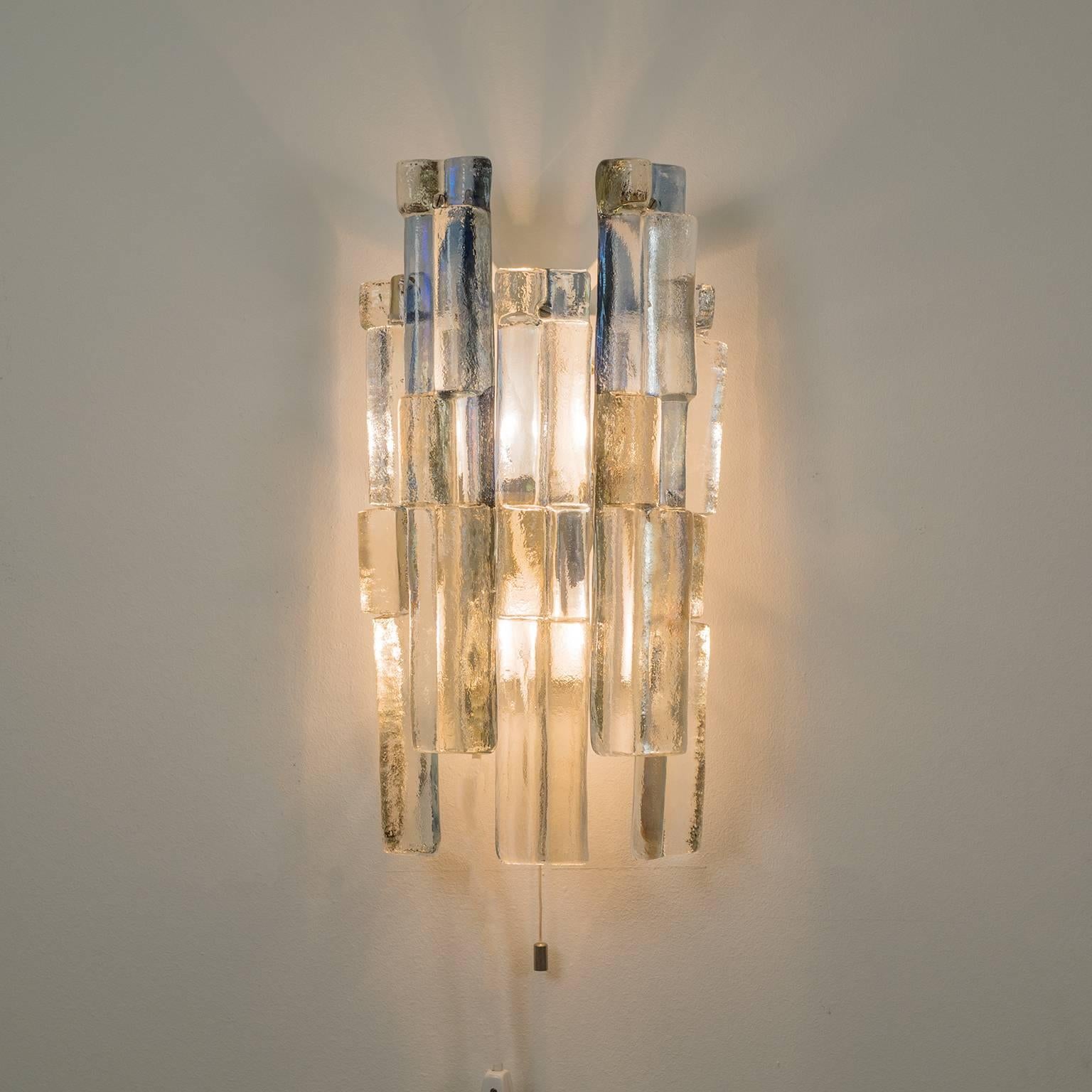 Rare large multicolored glass wall light by Kalmar, 1970s. Five long textured clear glass elements with blue and brown tinting are suspended on a Minimalist white lacquered metal backplate. Beautiful play of light and colors when lit by the two E14