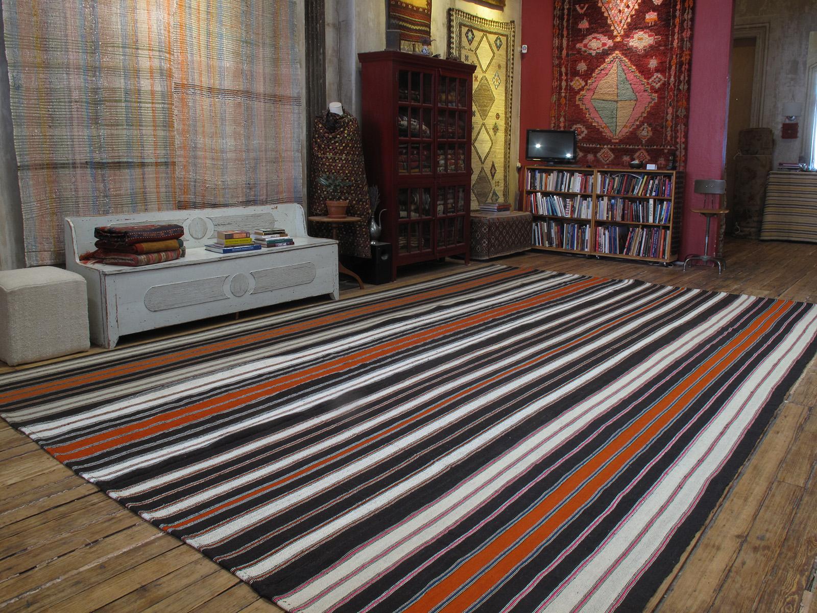 A very large tribal flat-weave from Southeastern Turkey, woven with goat hair in natural tones of dark brown and ivory, in addition to orange, pink and blue. A Kilim like this would have been used as a utilitarian, everyday floor cover in the