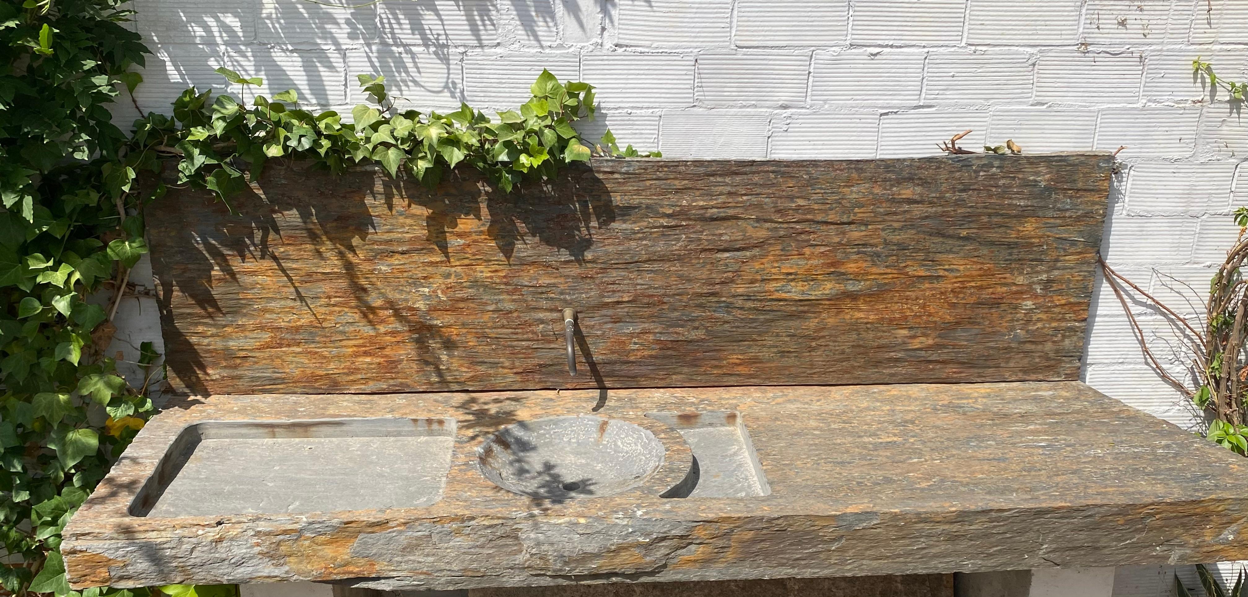 Este impresionante fregadero se fabricó a partir de un bloque macizo y sólido de esquisto natural oxidado. el bonito diseño de la pila y el escurridor se inspira en un modelo antiguo. su hermosa placa de pared embellece y da continuidad al conjunto.