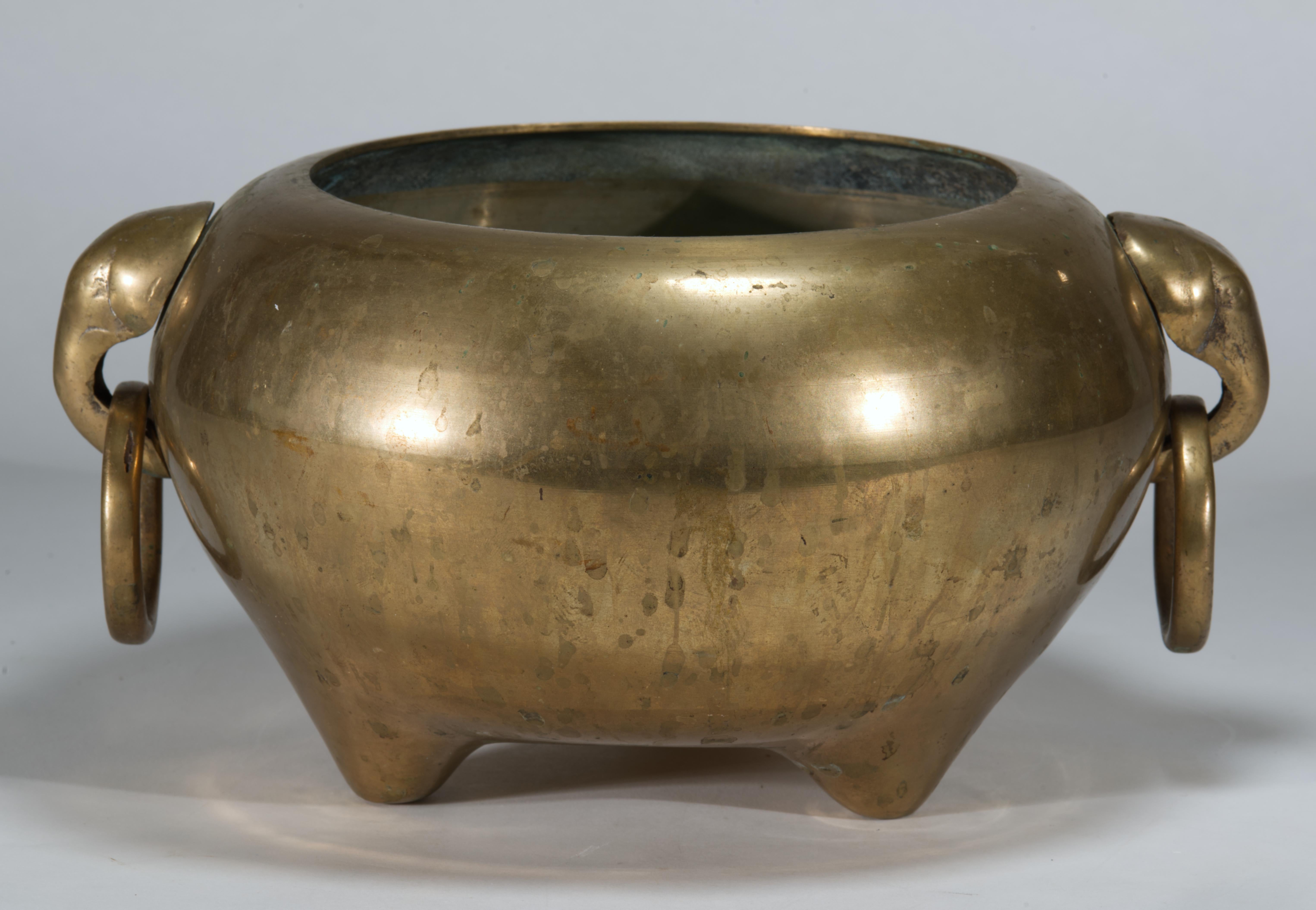 Das skulpturale Räuchergefäß aus Bronze im Vintage-Stil steht auf drei kurzen Füßen und ist mit zwei markanten Griffen mit Elefantenmaske ausgestattet. Der abgerundete, grafische Körper geht nahtlos in die robusten, stabilen Füße über und schafft so