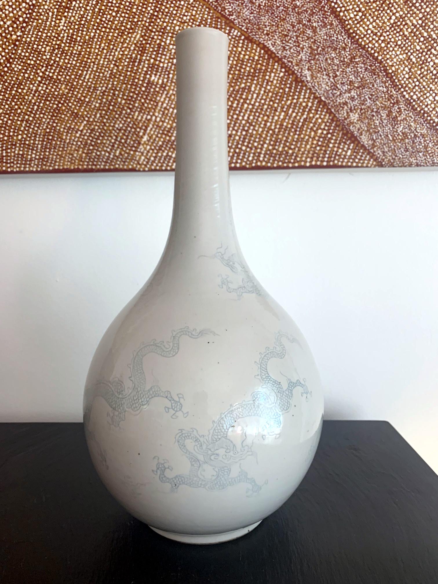 A large Korean dragon vase in an elegant classic form, with a straight neck and mouth and base rim. The white surface is subtly decorated with five blue underglaze flying dragons chasing flaming pearls. The white over glaze was applied in an