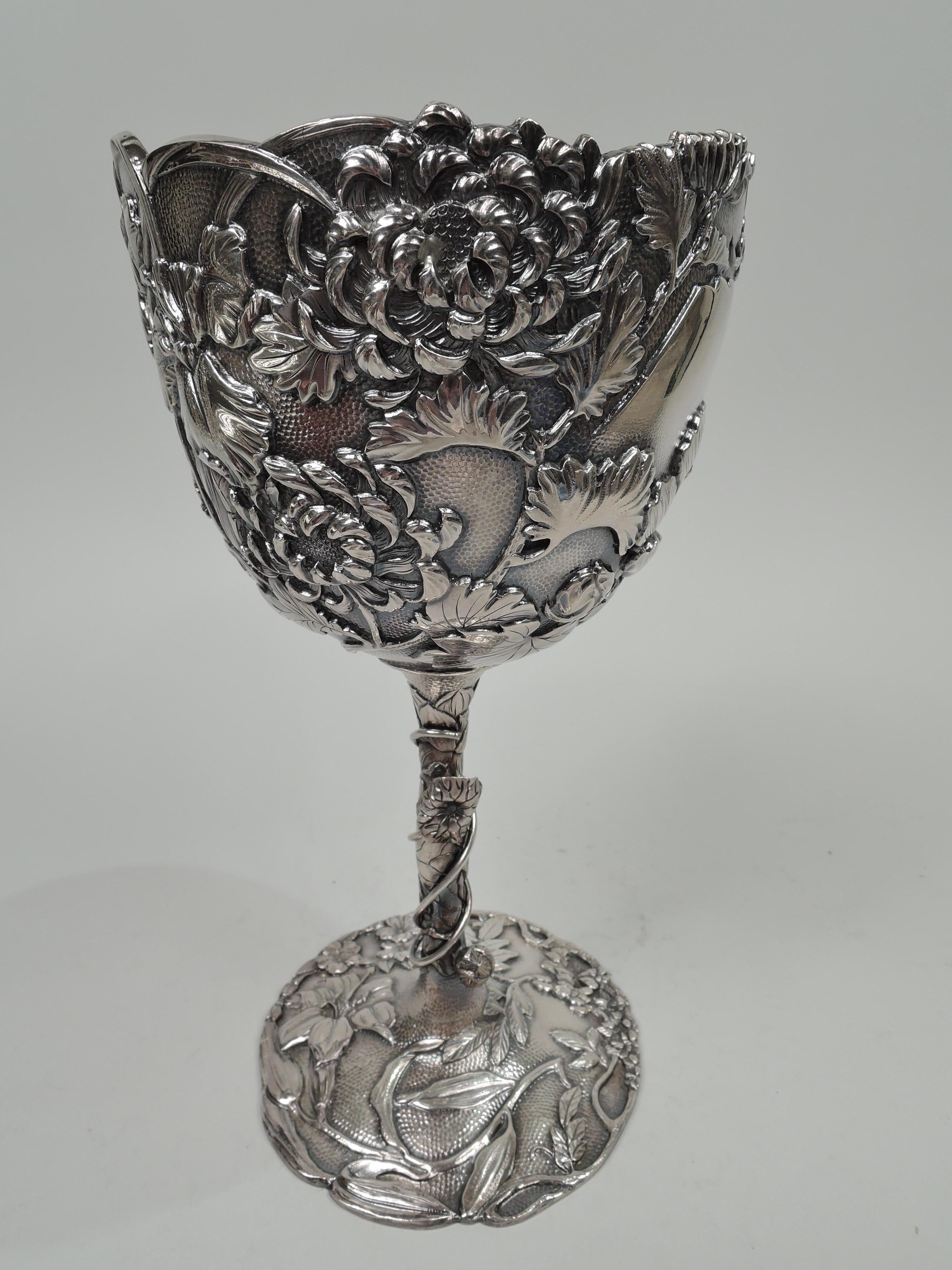Large Japanese Meiji silver chalice, ca 1890. Oval bowl with irregular rim on tall cylindrical shaft flowing into raised and scalloped foot. Spout hammered ground. Double walled. Applied iris and chrysanthemum flowers and blossoming branches. Wire