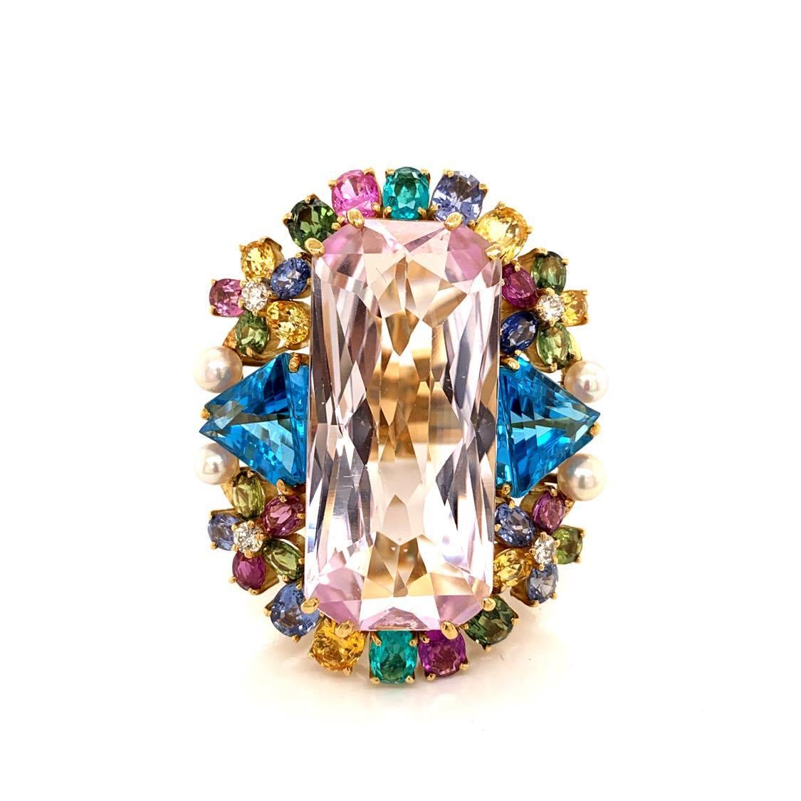 Wow! A guaranteed stunner! This large cocktail ring features a large rectangular shaped pink kunzite weighing 30 carats. Around the center stone is a bouquet of multicolored gemstones which include two fine paraiba tourmalines on the top and bottom
