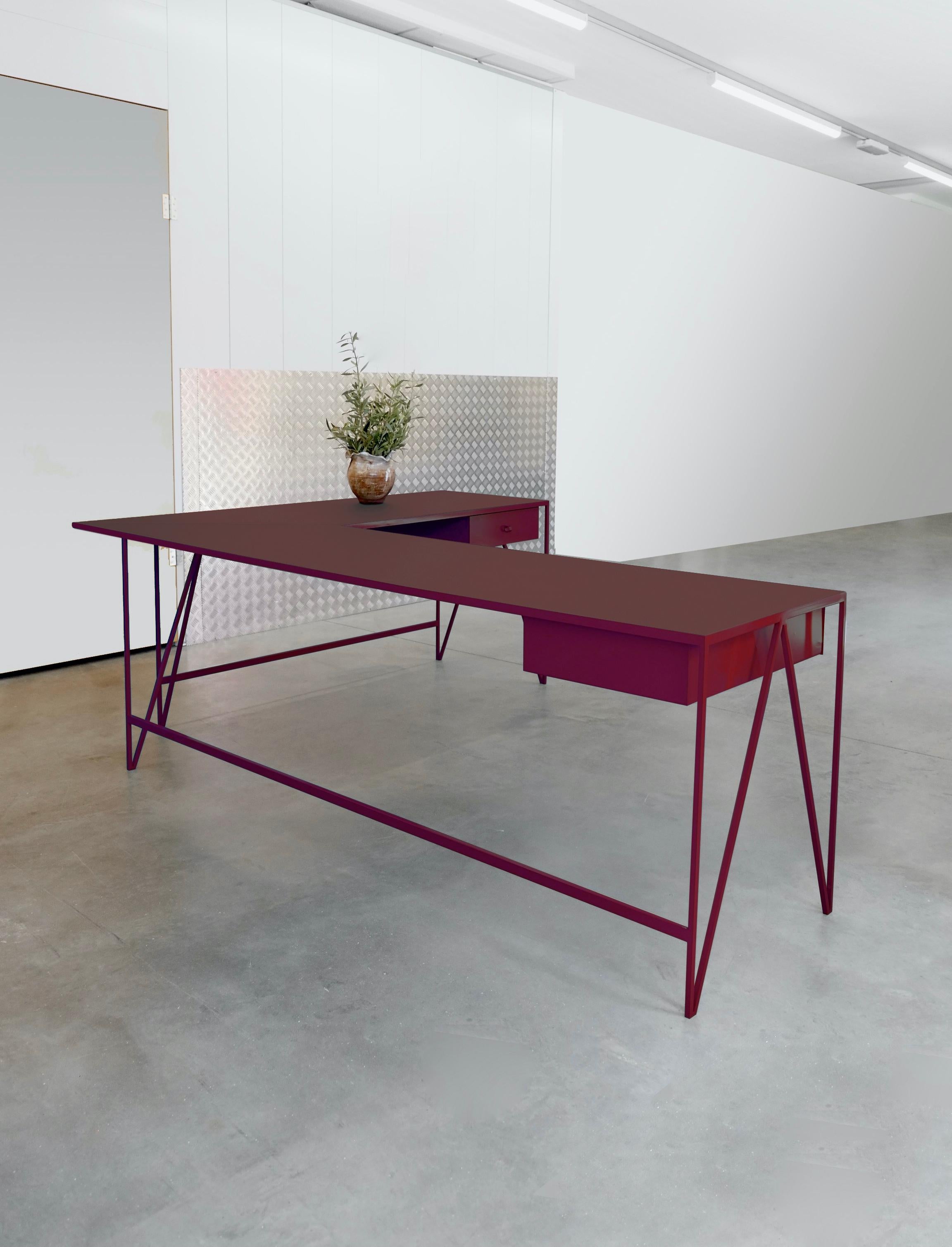 Un magnifique bureau d'étude en forme de L composé d'un cadre en acier revêtu par poudre de couleur bordeaux foncé et d'un plateau en linoléum de couleur assortie fabriqué à partir d'ingrédients entièrement naturels, tels que le lin, la farine de