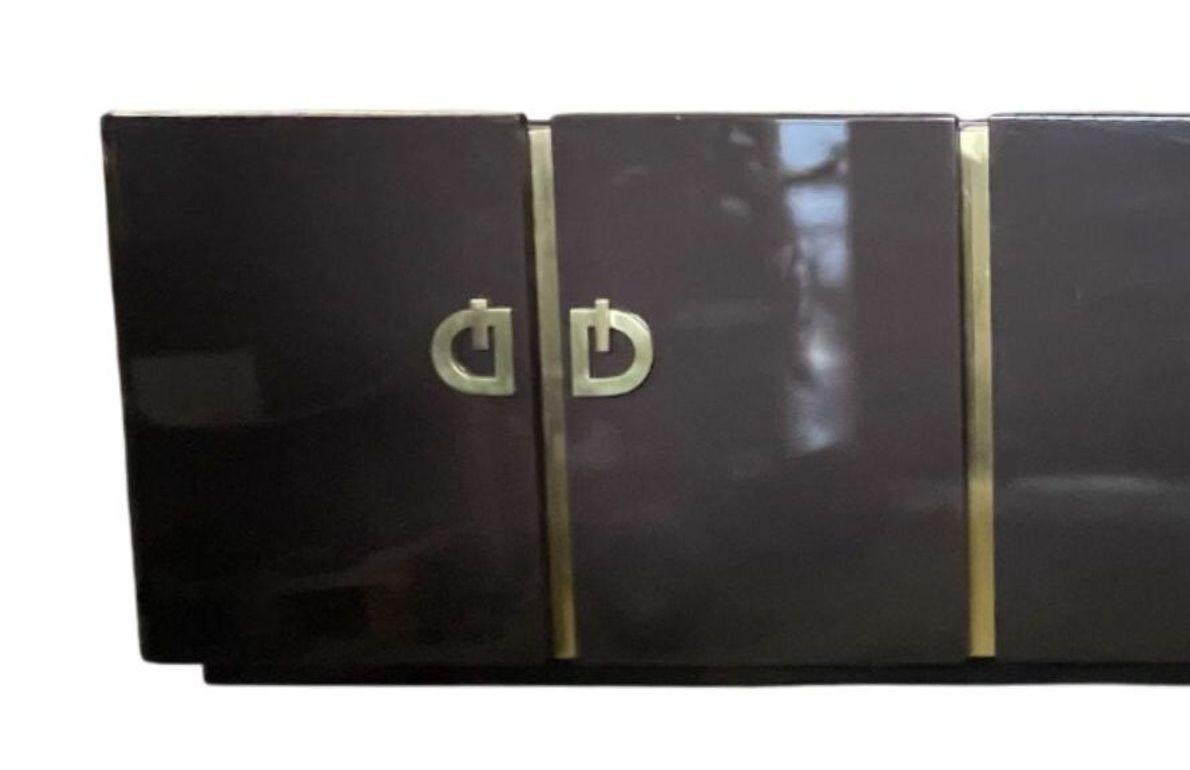 A striking large lacquered credenza/sideboard by Pierre Cardin, dating to circa 1960's. This sculptural piece features a sleek, high-gloss lacquered finish complemented by bold brass-mounted geometric accents, embodying the avant-garde aesthetic and
