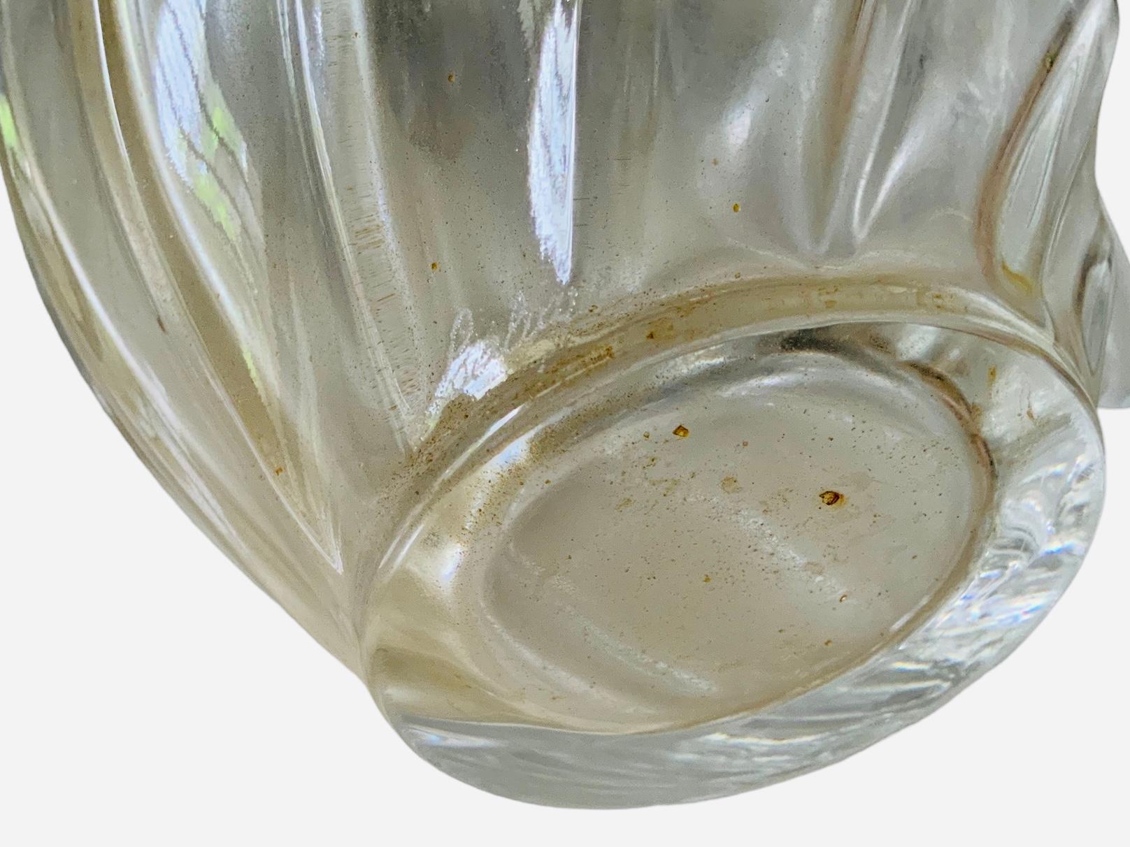 This is a big Lalique clear and frosted crystal perfume bottle of L’Air du Temps. It is a pear shaped  ribbed bottle enhanced by two large frosted crystal doves that are flying and kissing stopper. In one of the bottle bottom side is etched the