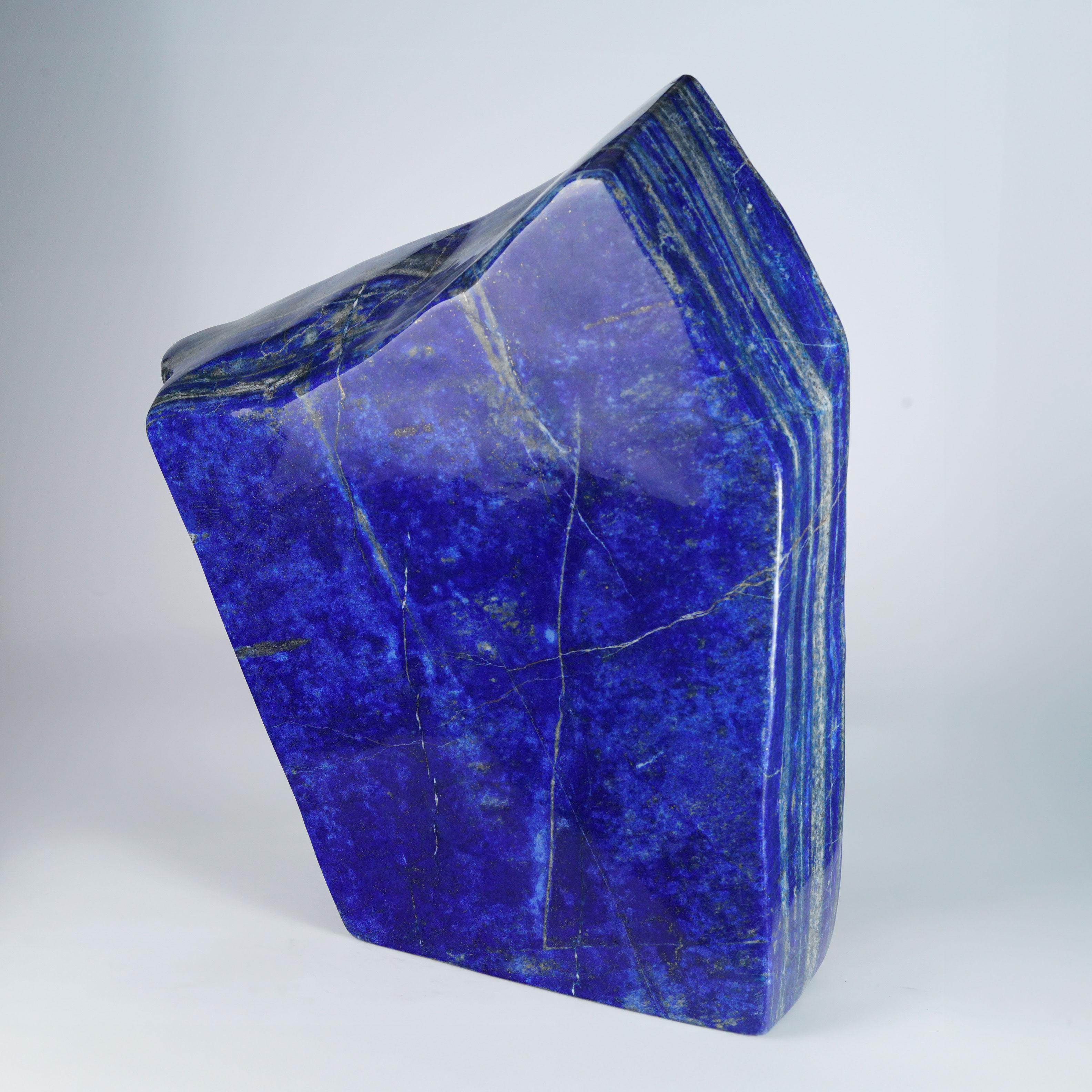 Diese große, glänzend handpolierte Lapislazuli-Freiform ist eine auffällige Naturskulptur, die sowohl Innen- als auch Außenbereiche aufwertet. Sein kräftiger Kobaltton und seine eleganten Linien - mit Einschlüssen von Kalzit und schimmerndem