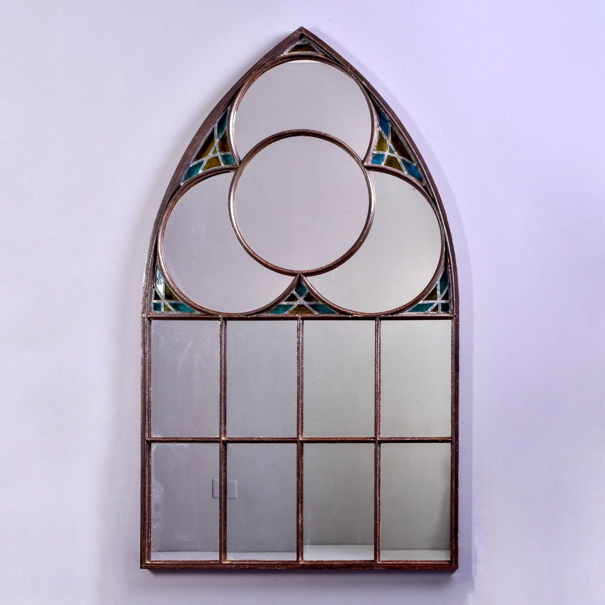Found in France, this circa 1890s iron framed church window with stained glass has been refitted with a mirror. Stands over five feet tall. Original church is unknown.