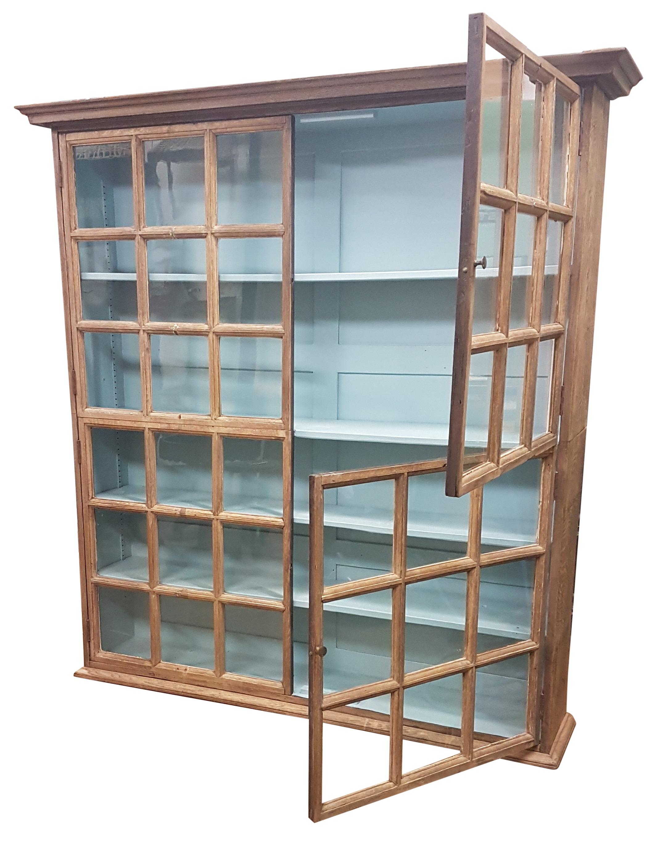 A very nice and decorative solid oak glazed bookcase that has been bleached to give a weathered oak look with the inside being a pastel blue colour. The front is fully glazed and much of the original glazing is in place and has nice rippling to the