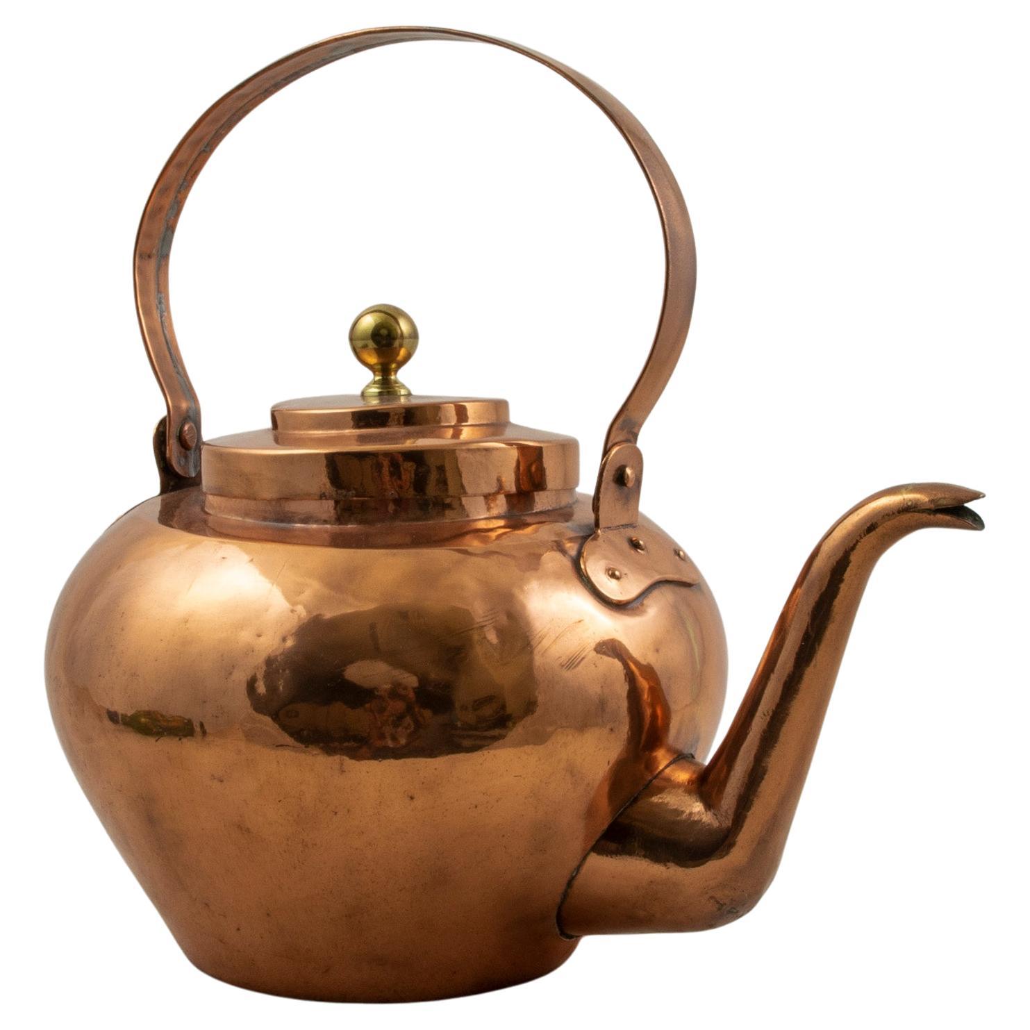 This large scale nineteenth century French copper tea kettle features a copper riveted handle and lid appointed with a brass knob. The tea kettle measures 16 inches in height by 11 inches in diameter, and measures 16 inches wide with spout. c. 1900.