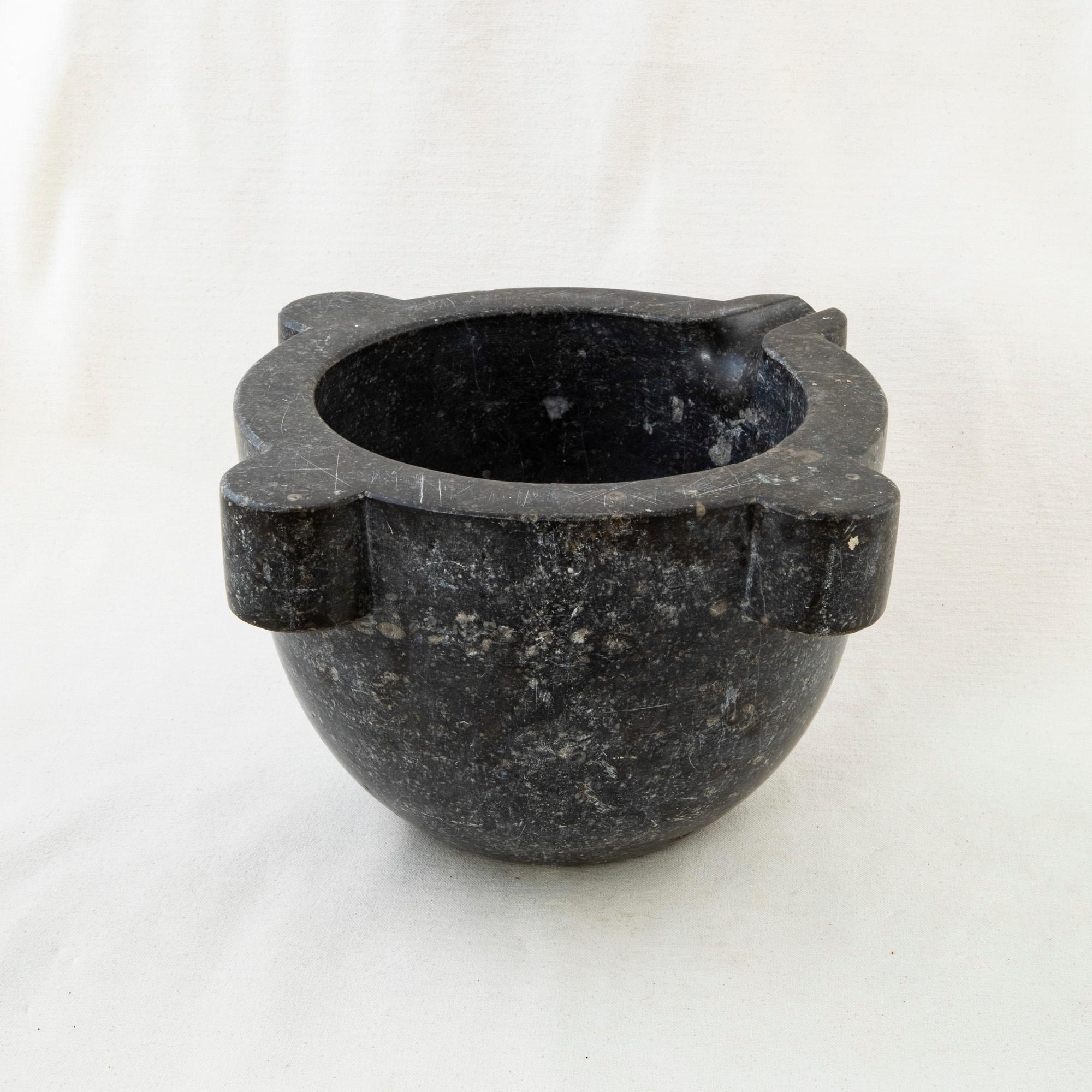 This late 19th century marble mortar is made from a single block of black marble. Large in size, this piece was once used with its accompanying pestle by a pharmacist to grind herbs for medicinal purposes, it can now serve as a planter, bowl, or