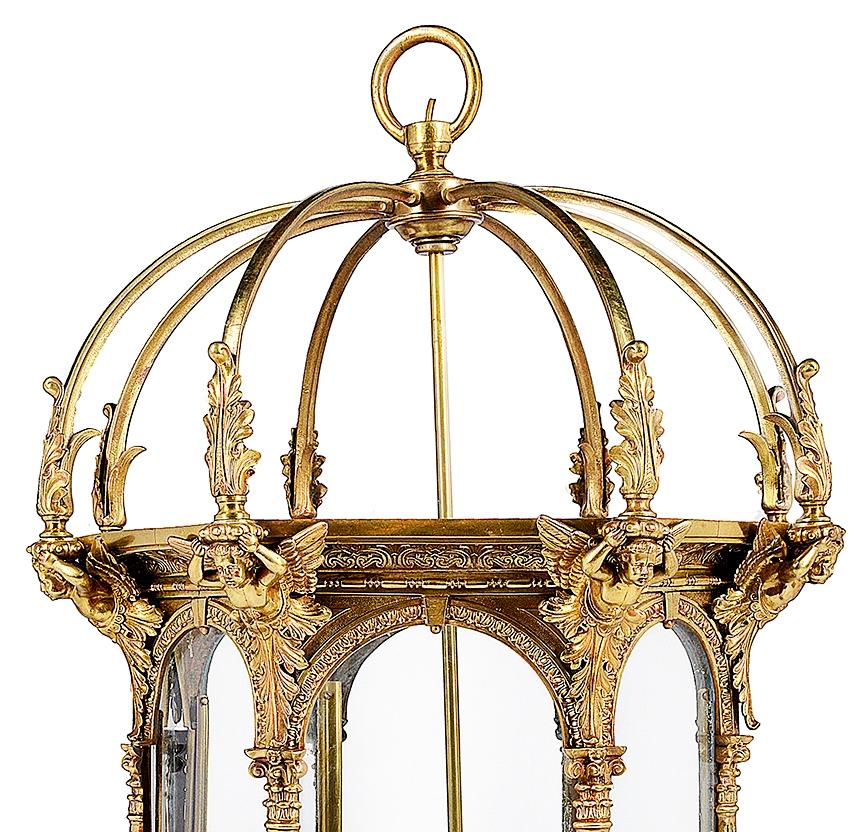 A large and impressive classical late 19th century ormolu lantern, having arched supports above, scrolling foliate and cherub mounts, arched panels and Corinthian columns, terminating in classical motif feet. Measures: 95 cm (37”).