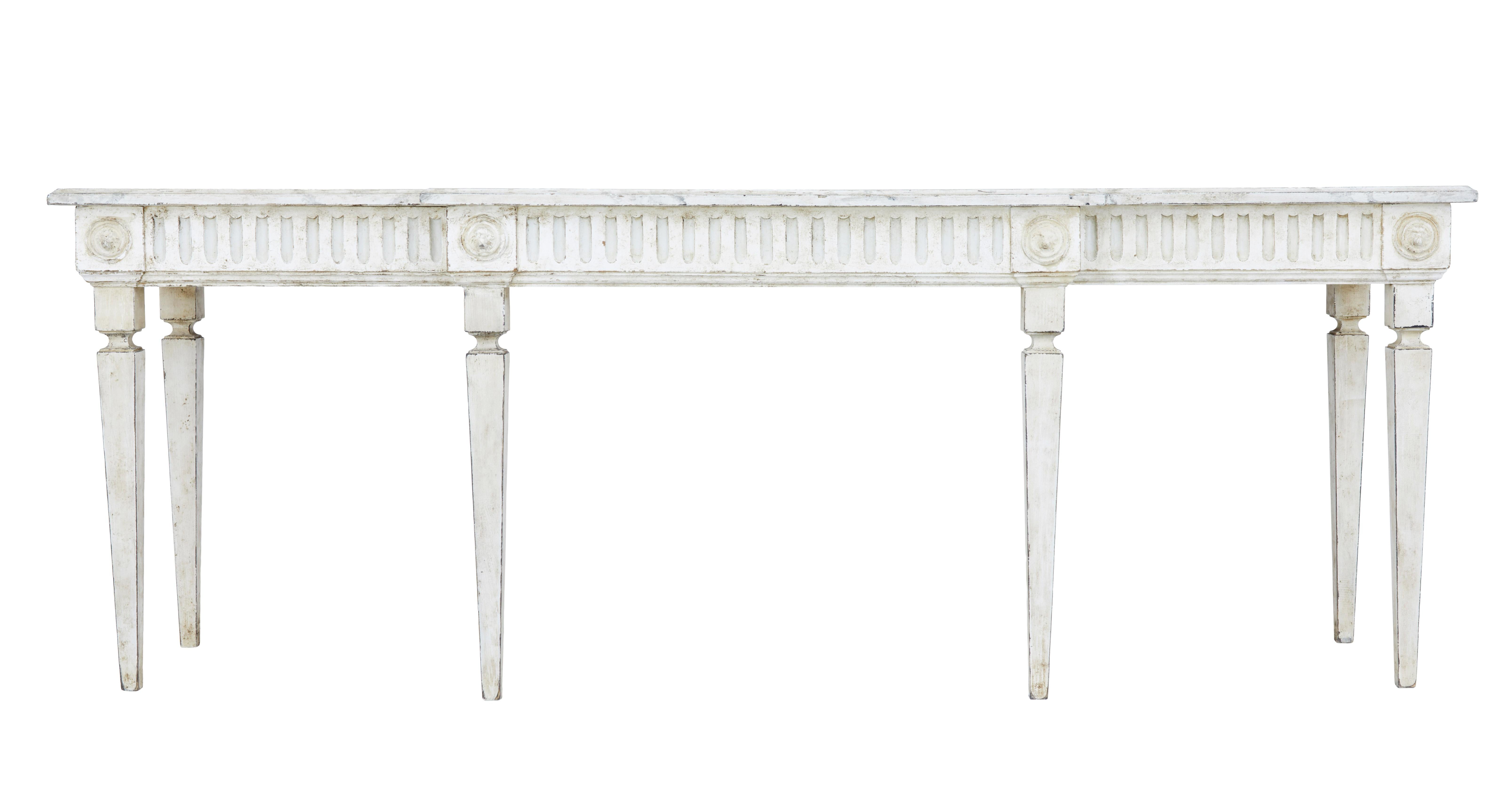 Grand large painted Swedish console table in the Gustavian taste, circa 1890.

Breakfront shaped with hand painted faux marble top, fluted detailing along the frieze with applied lion mask roundels.

Standing on 6 tapered legs.

Later paint
