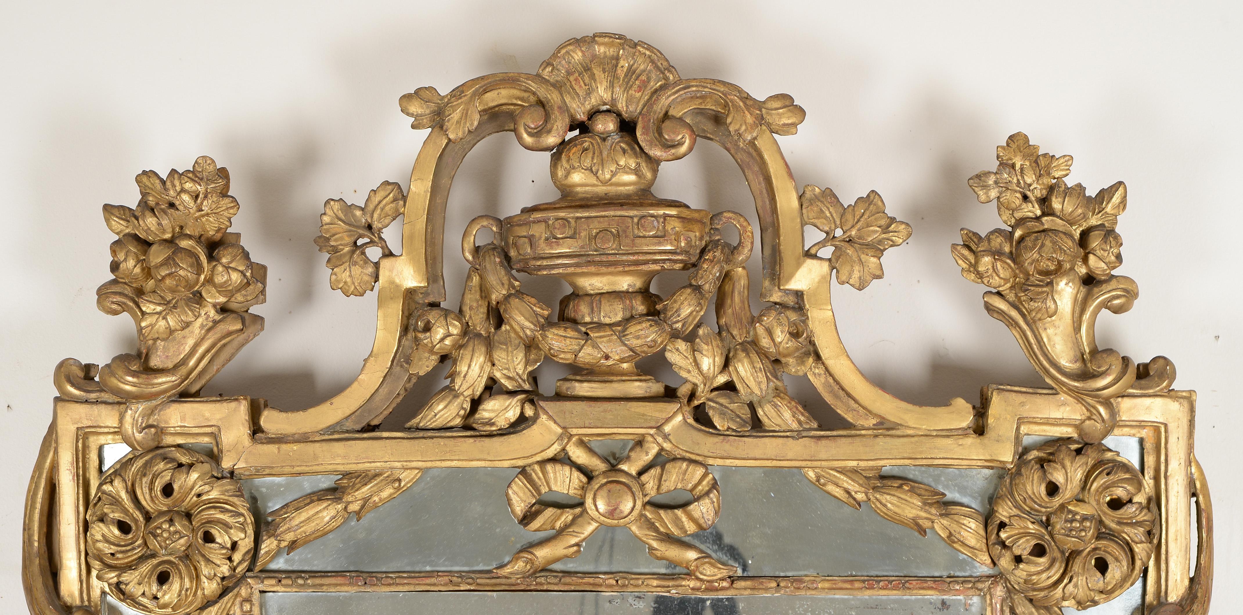 Rare miroir en bois doré 'A La Grecque' de la fin de Louis XV
La plaque rectangulaire divisée est surmontée d'un trophée en forme d'urne flanqué de vases fleuris de chaque côté et suspendu à des guirlandes de campanules. 

Par sa décoration et sa