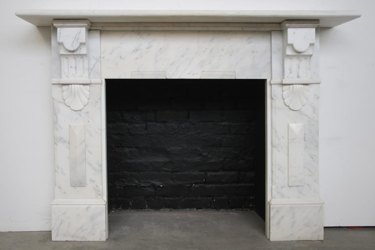 A large late Victorian Carrara marble fireplace with large architectural corbels and lozenge decoration to the jambs.

Removed from a large house in Chorlton, Manchester, England.

For detailed sizes please see the size diagram in the image