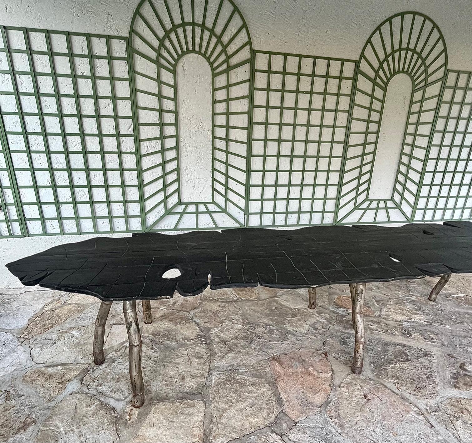 Ein großer Esstisch (Bauernhoftisch)  oder Erntetabelle )
Die  Die Tischplatte aus gebeiztem Holz hat die Form eines Blattes mit Stiel und Adern.
Diese Platte ruht auf 3 