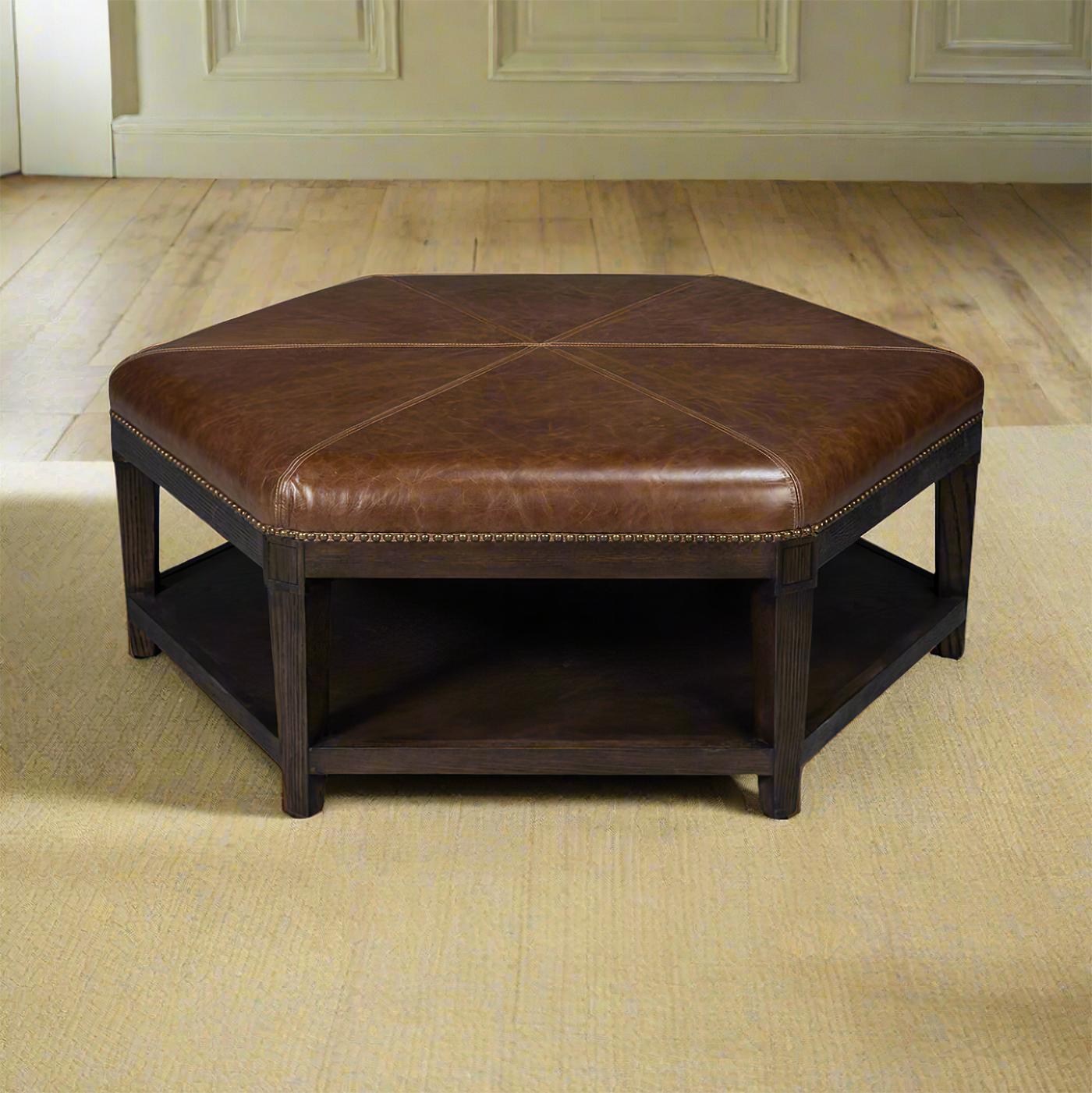 Crafted with a solid wooden frame and a rich dark finish, this ottoman is both sturdy and stylish. The classic traditional top grain leather upholstered top provides a comfortable seating option or a chic coffee table alternative. Adorned with brass