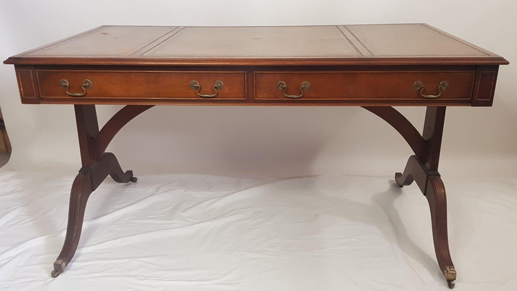 Large Georgian style mahogany writing table by Reprodux.

Having a lovely antique style tooled leather writing surface in three sections. Front opening drawers and rear dummy drawer fronts. 

Raised on twin end supports having splayed feet, with