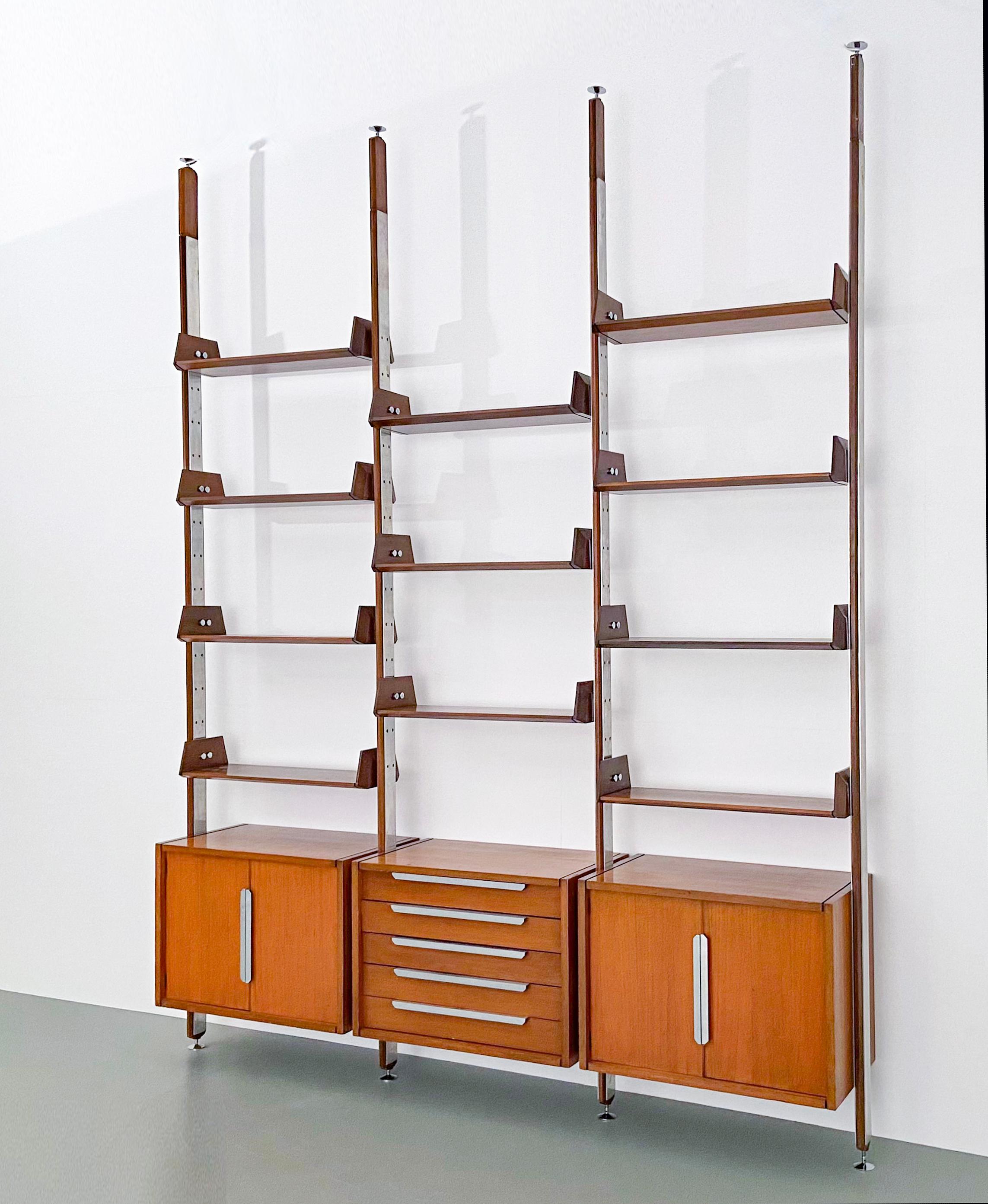 Large library in teak and metal.

These shelves can very well be used as a room divider too because the back side is the same as the front side with the same details such as the inward falling back plates and the small black carved stripes.