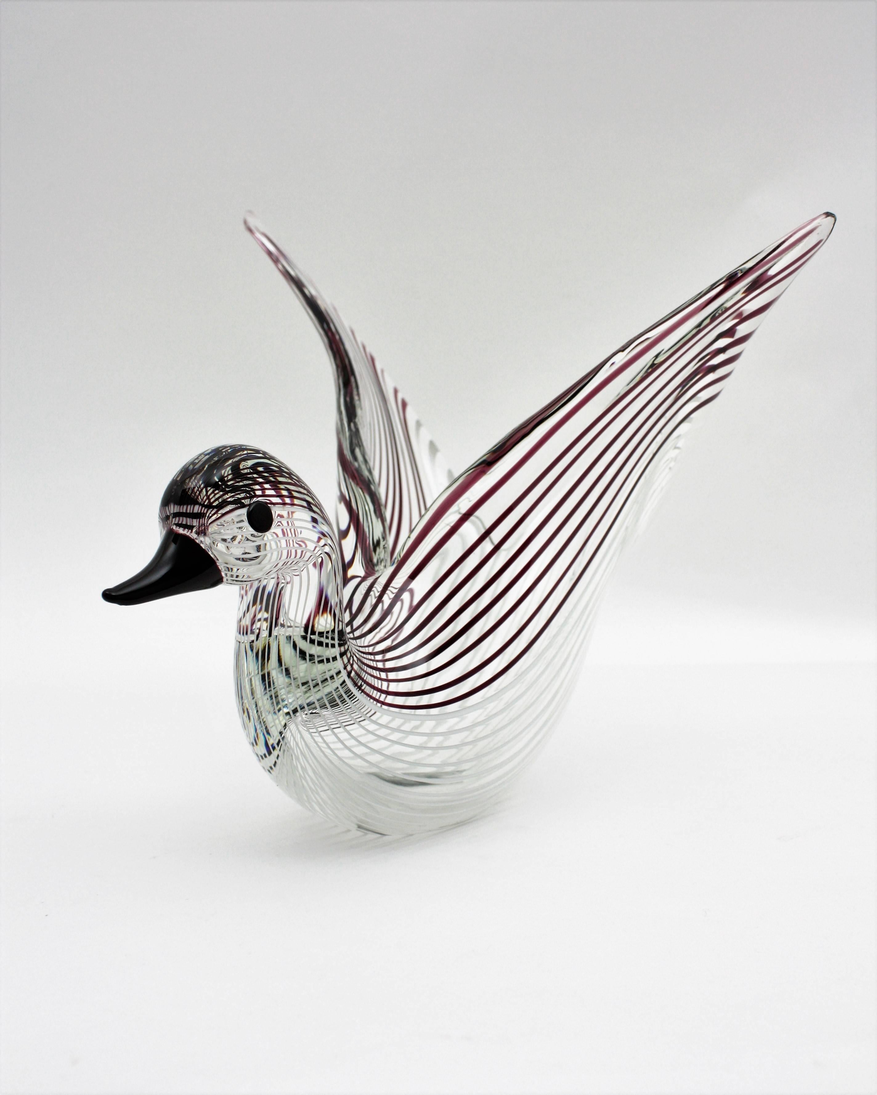 Elegant Murano glass duck figure / sculpture with ribbons in white and burgundy colors by Licio Zanetti. Italy, 1960-1970.
This exquisite large sized Murano glass centerpiece features a hand blown clear glass duck figure with open wings with