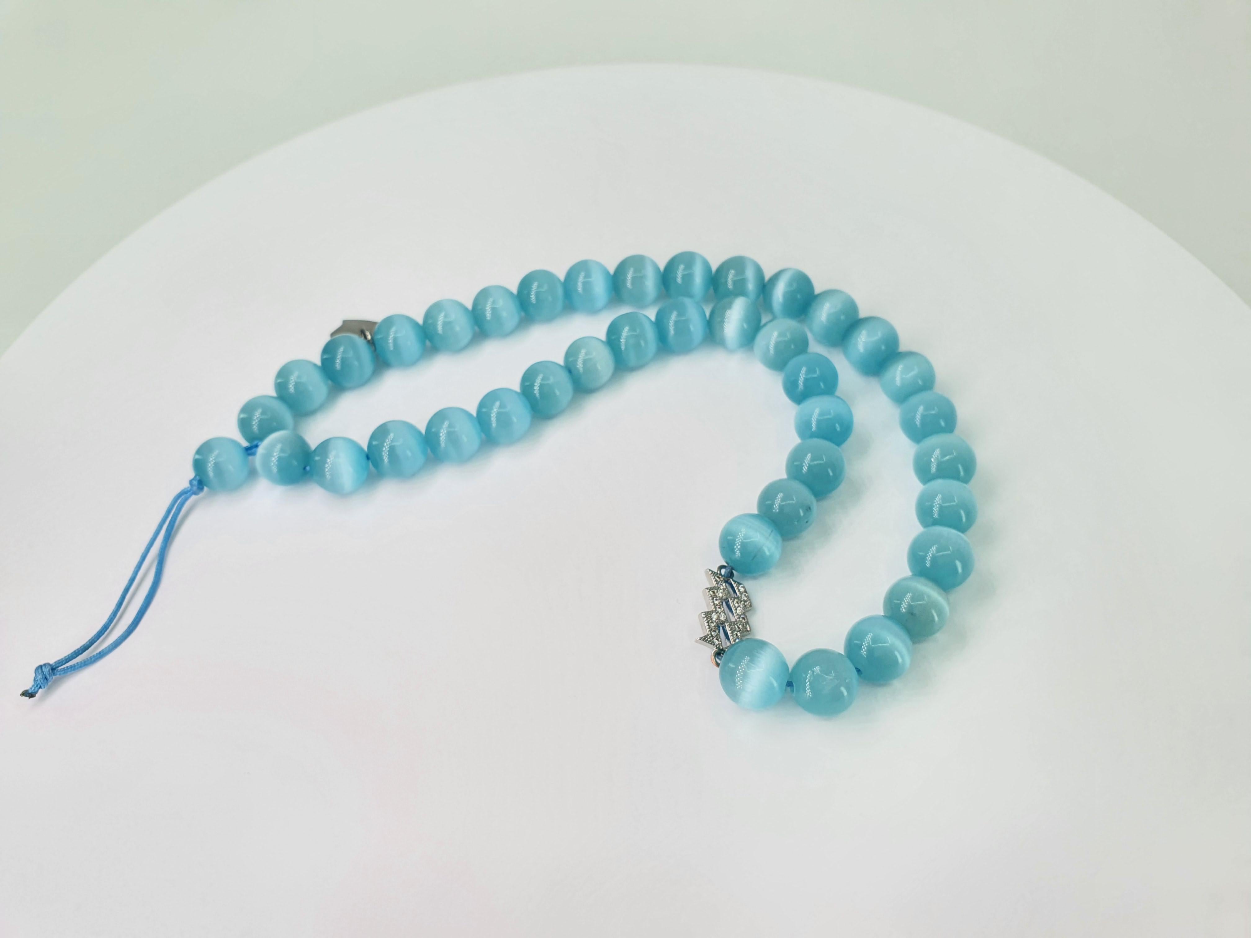 This beautiful light blue cat eye beads and aquarius charm Strap can be used as an accessory for a phone, for a hand bag or a clutch.
  The strap is carefully handcrafted by our artisans. 
