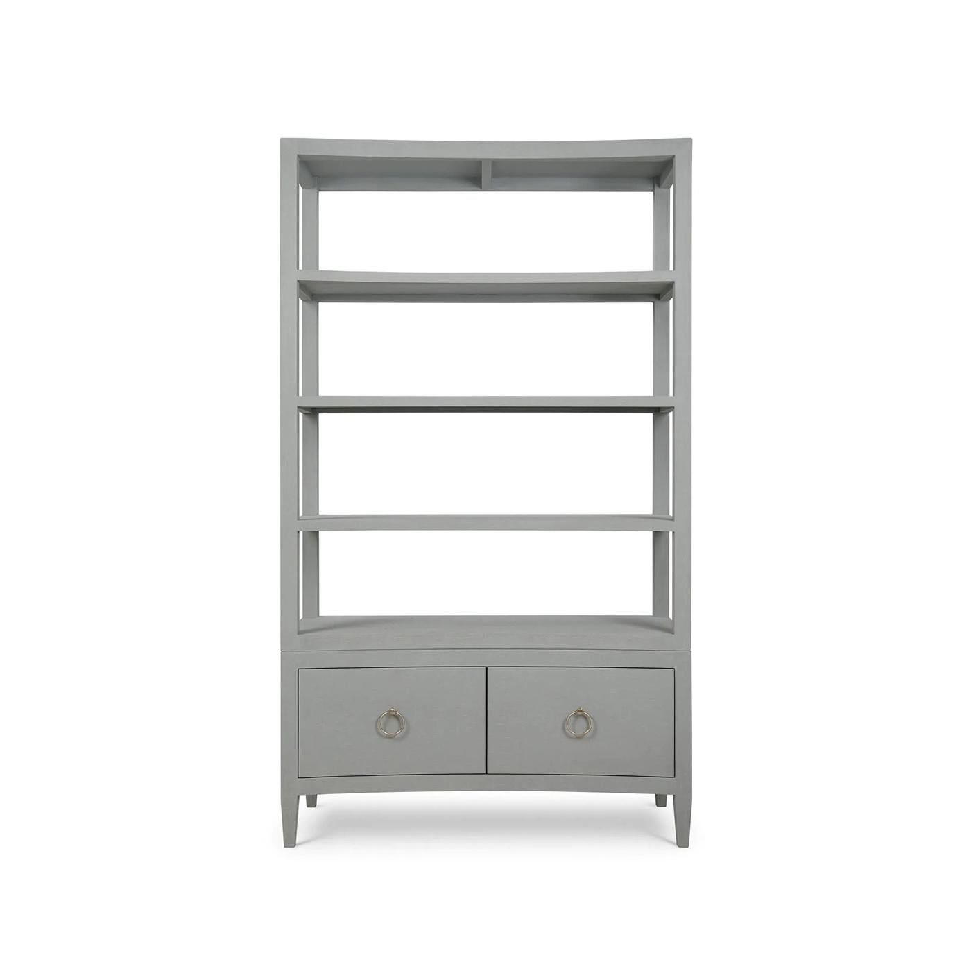 Wrapped in soft pale blue linen, this tall shelving unit features a subtly concave front that introduces movement and elegance to its minimalist profile. Four open shelves offer ample space for display, while two lower drawers with ring-pull