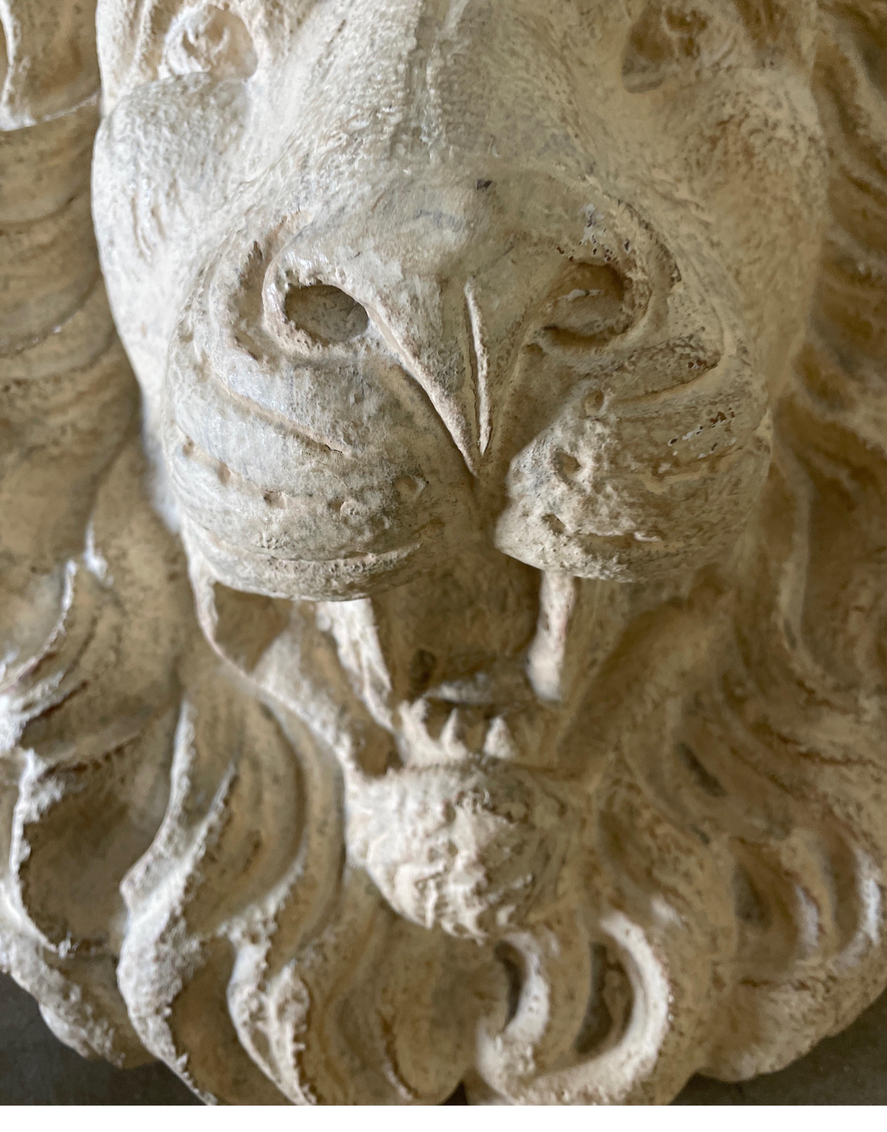 Sculpture murale représentant une tête de lion majestueuse.