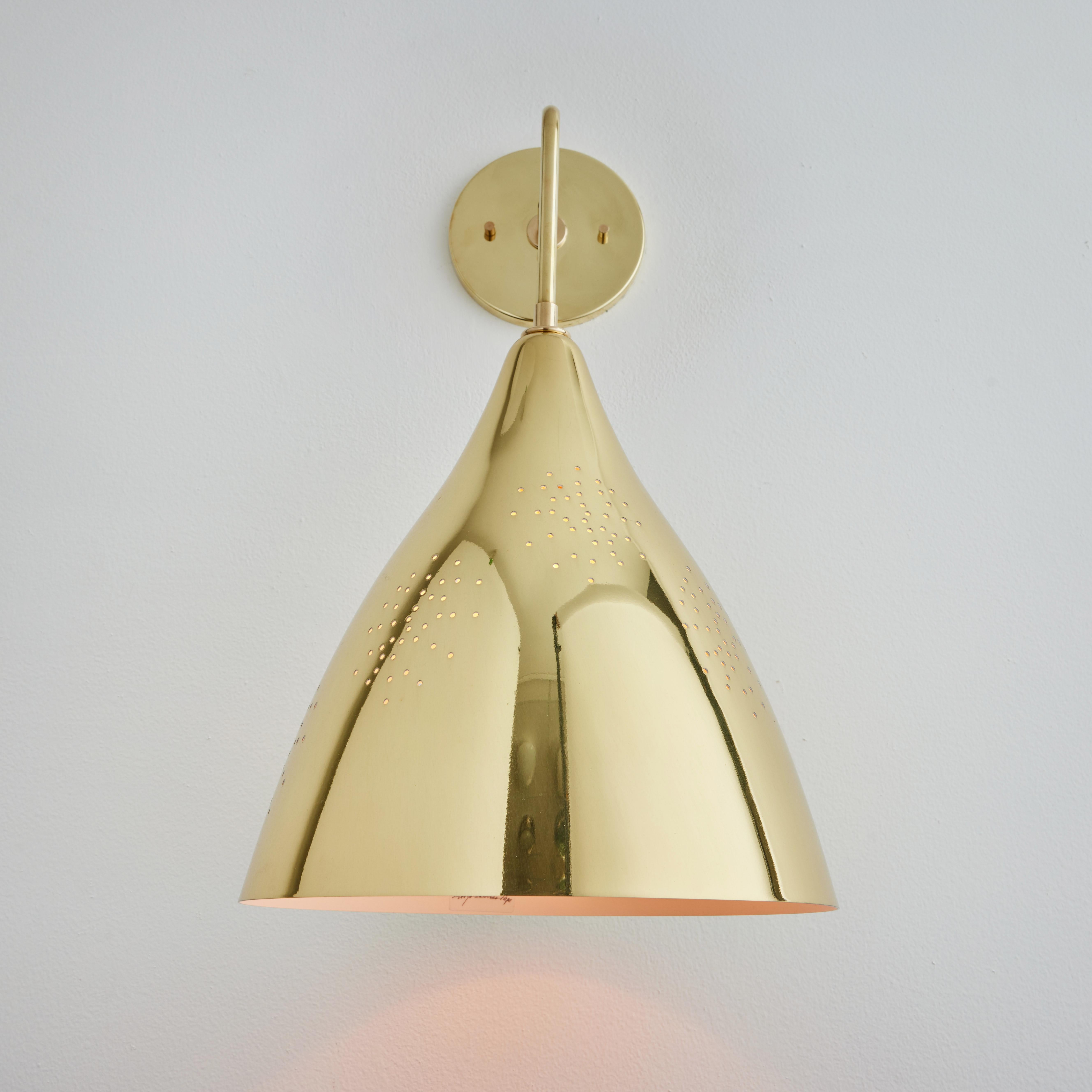 Large Lisa Johansson-Pape '270' perforated brass wall lamp. Originally designed in 1947, these custom modified authorized re-editions are true to the original charming simplicity of Pape's iconic Finnish design. The white interior of each metallic