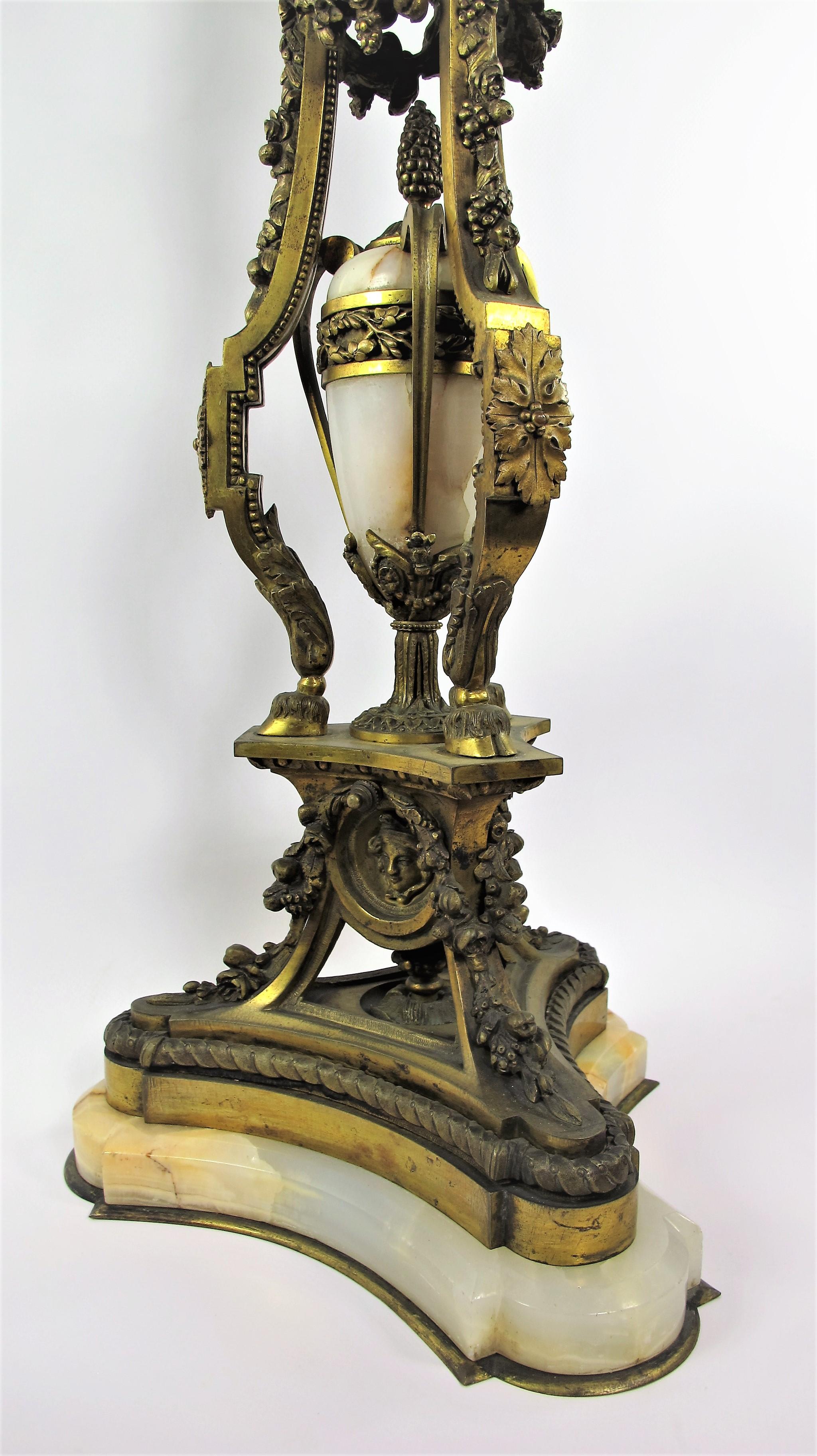 Important living room lamp in chiseled and gilded bronze and onyx marble from Algeria in Louis XVI style. Rich decoration of garlands of flowers, fruits and draperies, missing the shade. The base is tripod-shaped, the center is decorated with a fire