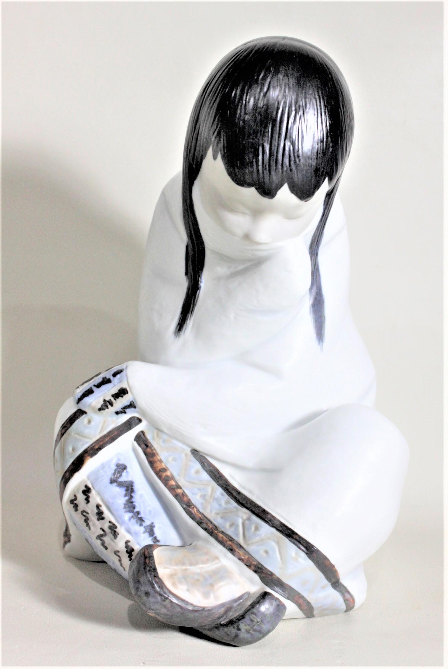 Diese sehr große, handbemalte Porzellanfigur wurde von der renommierten Firma Llladro in Spanien etwa 1985 hergestellt. Die Figur stellt ein junges Inuit-Mädchen dar, das im Schneidersitz mit gesenktem Kopf sitzt. Die handgemalten Details sind in