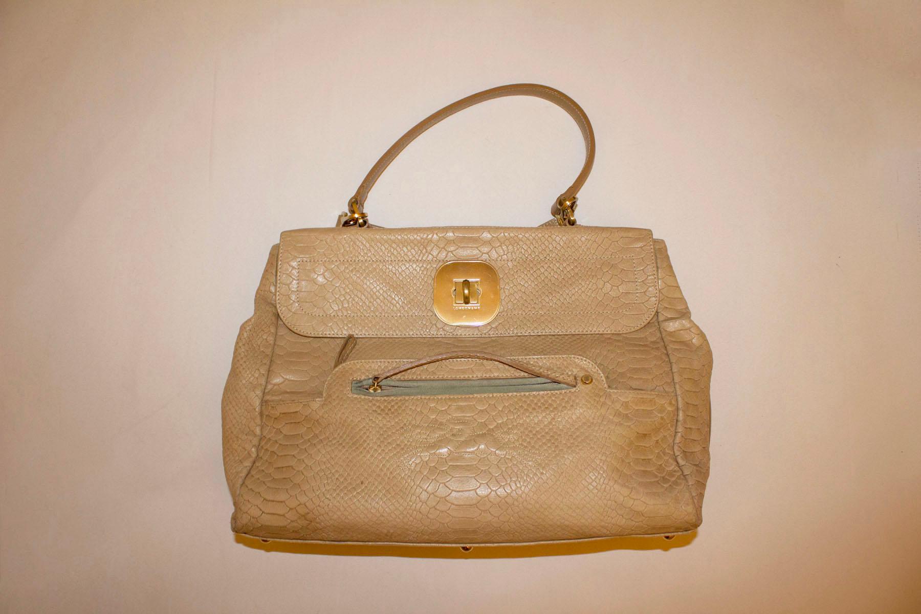 A wonderful caramel colour leather bag by Longchamp. The bag is top handle, with a detachable shoulder strap.
It has a flap front opening, with an external zip pocket. Internally there is one zip pocket and two pouch pockets.
The bag has stud feet,
