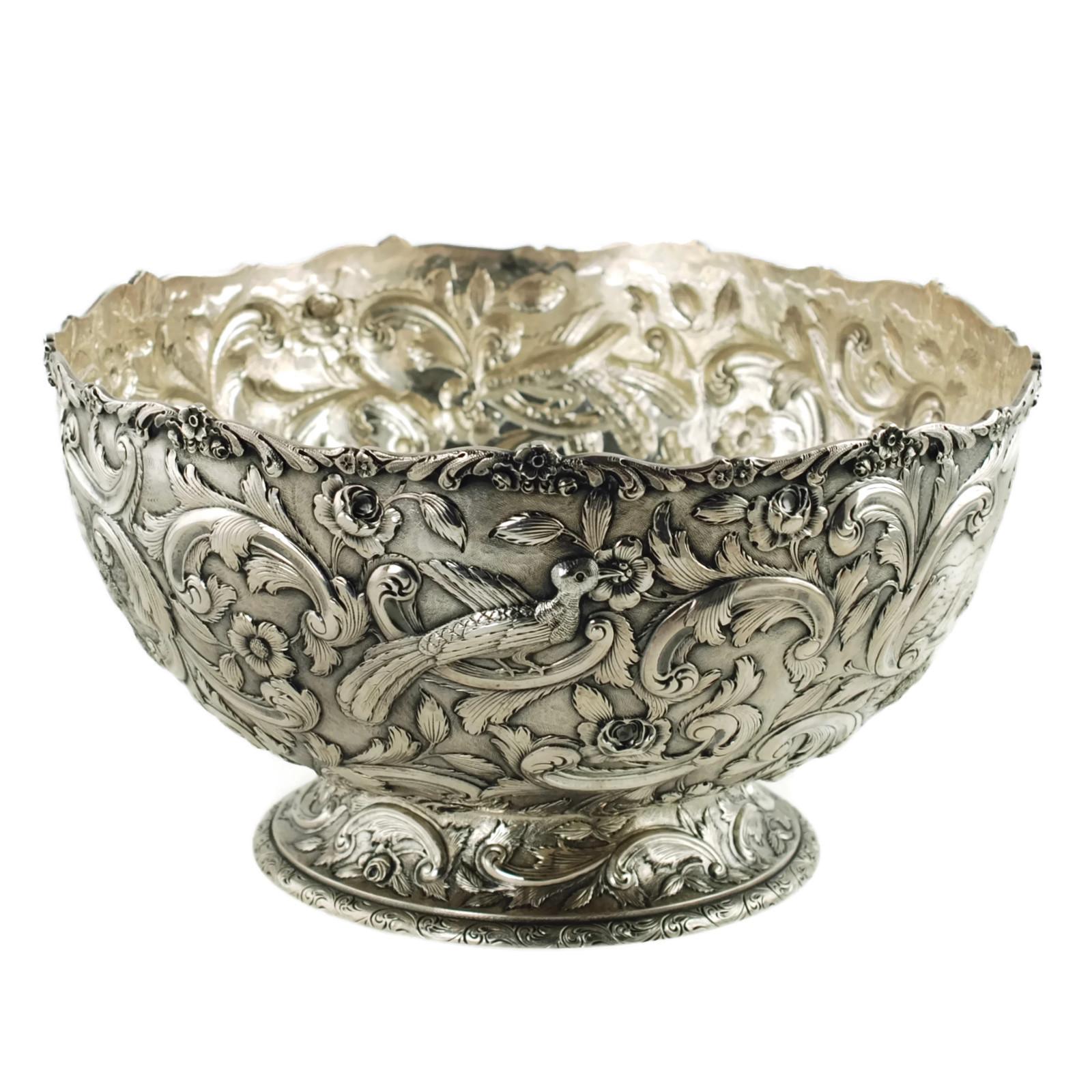This large ornate early 20th century sterling silver footed punch bowl has been made in the Castle pattern and was retailed by The Loring Andrews Company of Cincinnati. The footed bowl features highly detailed all-over repoussé decoration which